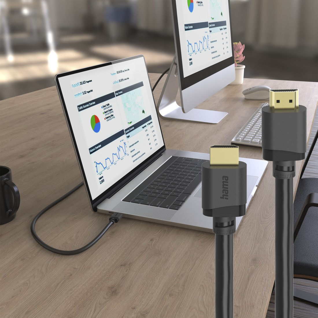 Un ordinateur portable et un moniteur affichent des analyses sur un bureau. Deux câbles HDMI au premier plan.