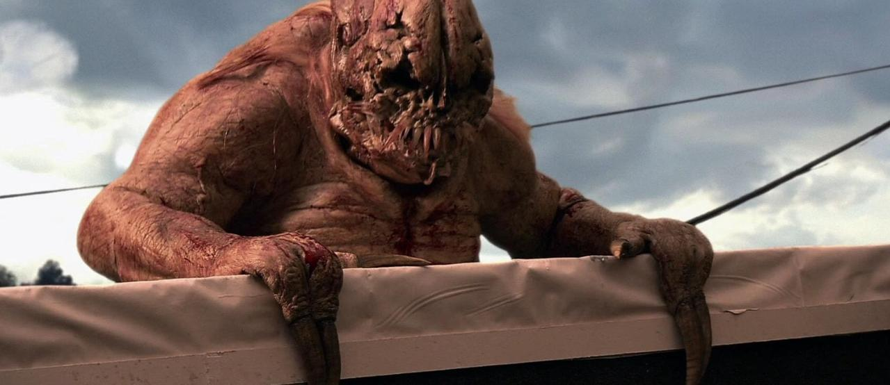 Ein gruseliges, fleischiges Monster mit Klauen klettert über eine weiße Plane.