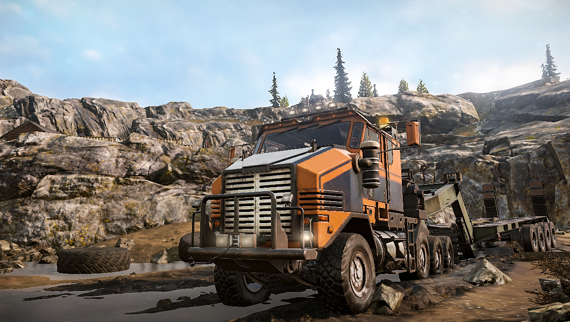 Pomarańczowy holownik z przyczepą stoi w skalistym krajobrazie.