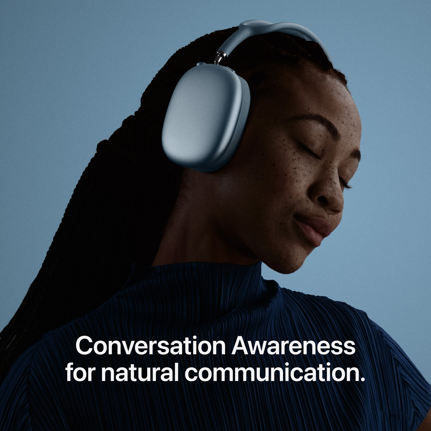 A woman with closed eyes wears light blue headphones against a blue background.
