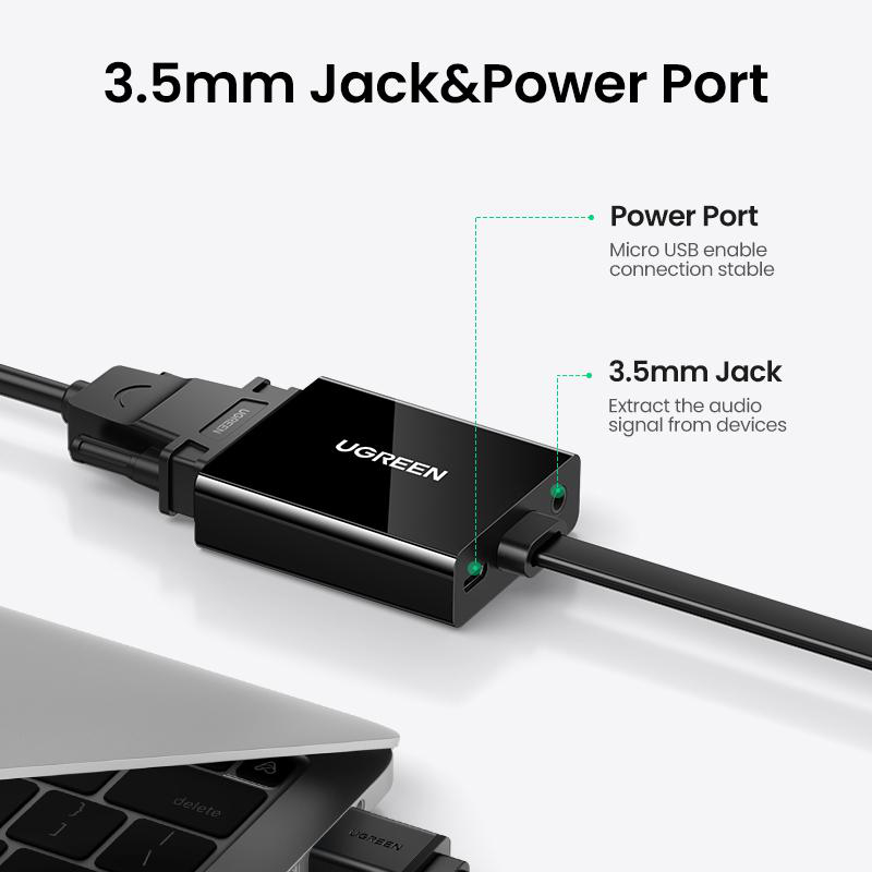 Schwarzer UGREEN Adapter mit 3,5mm Klinken- und Micro-USB-Anschluss neben einem Laptop.