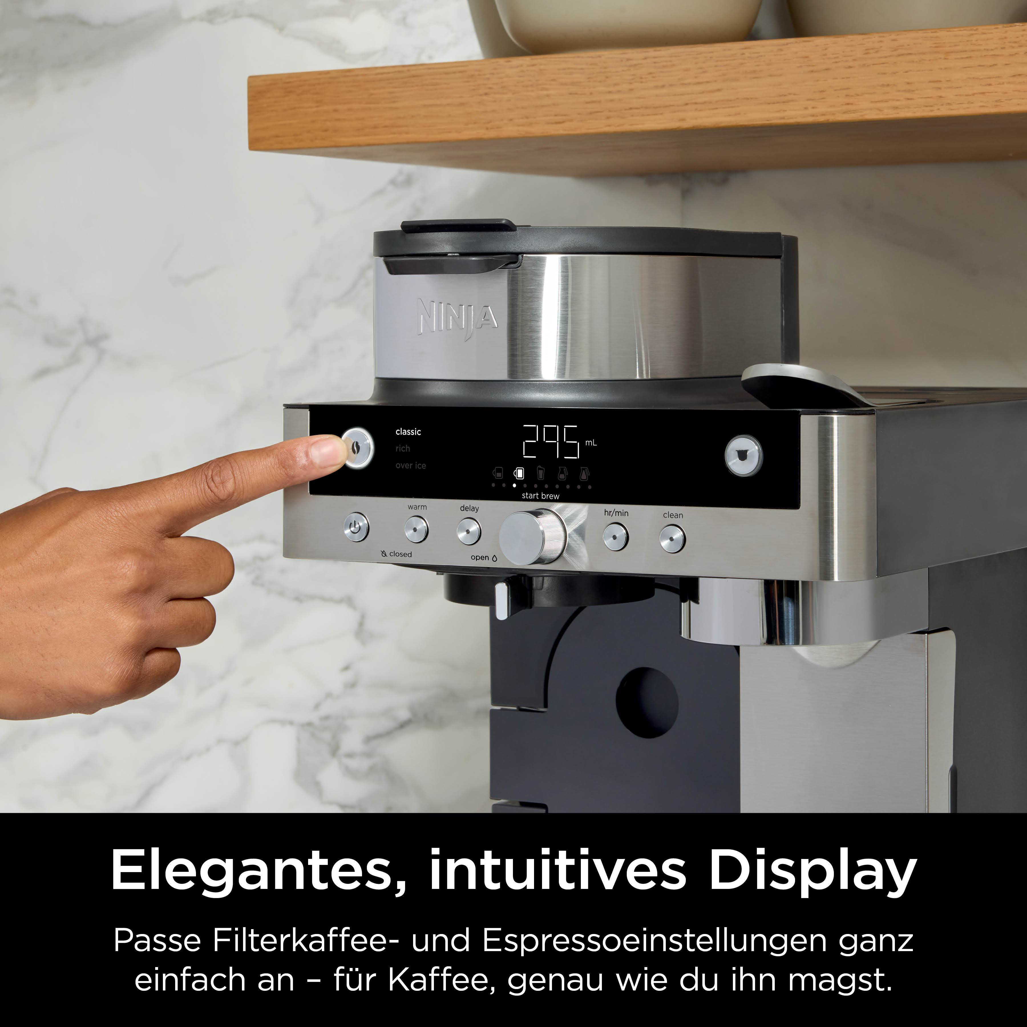 Eine Hand drückt eine Taste auf einer Kaffeemaschine mit digitalem Display.