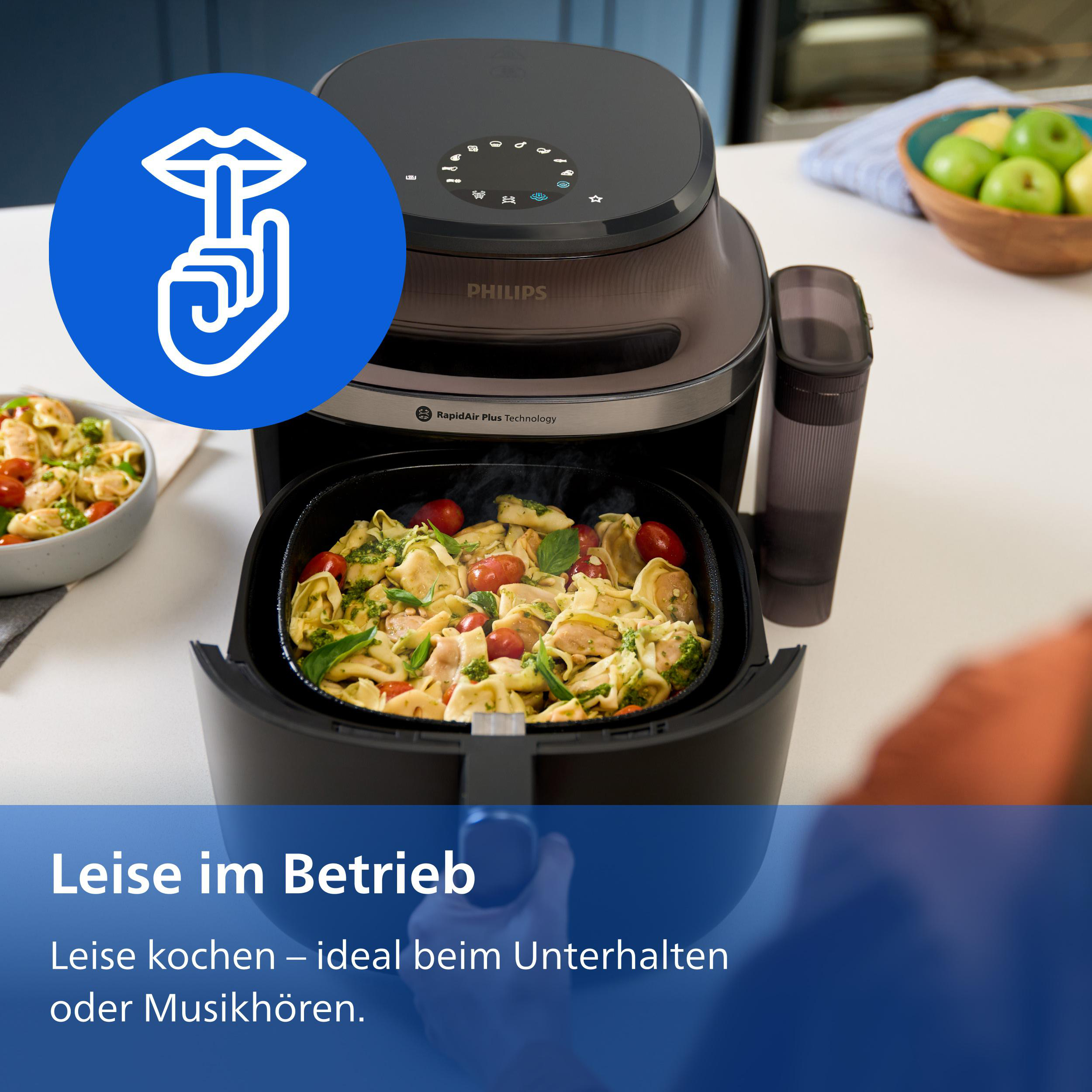 Airfryer mit Tortellini und Tomaten. Blaues Symbol mit "Ruhe"-Geste.
