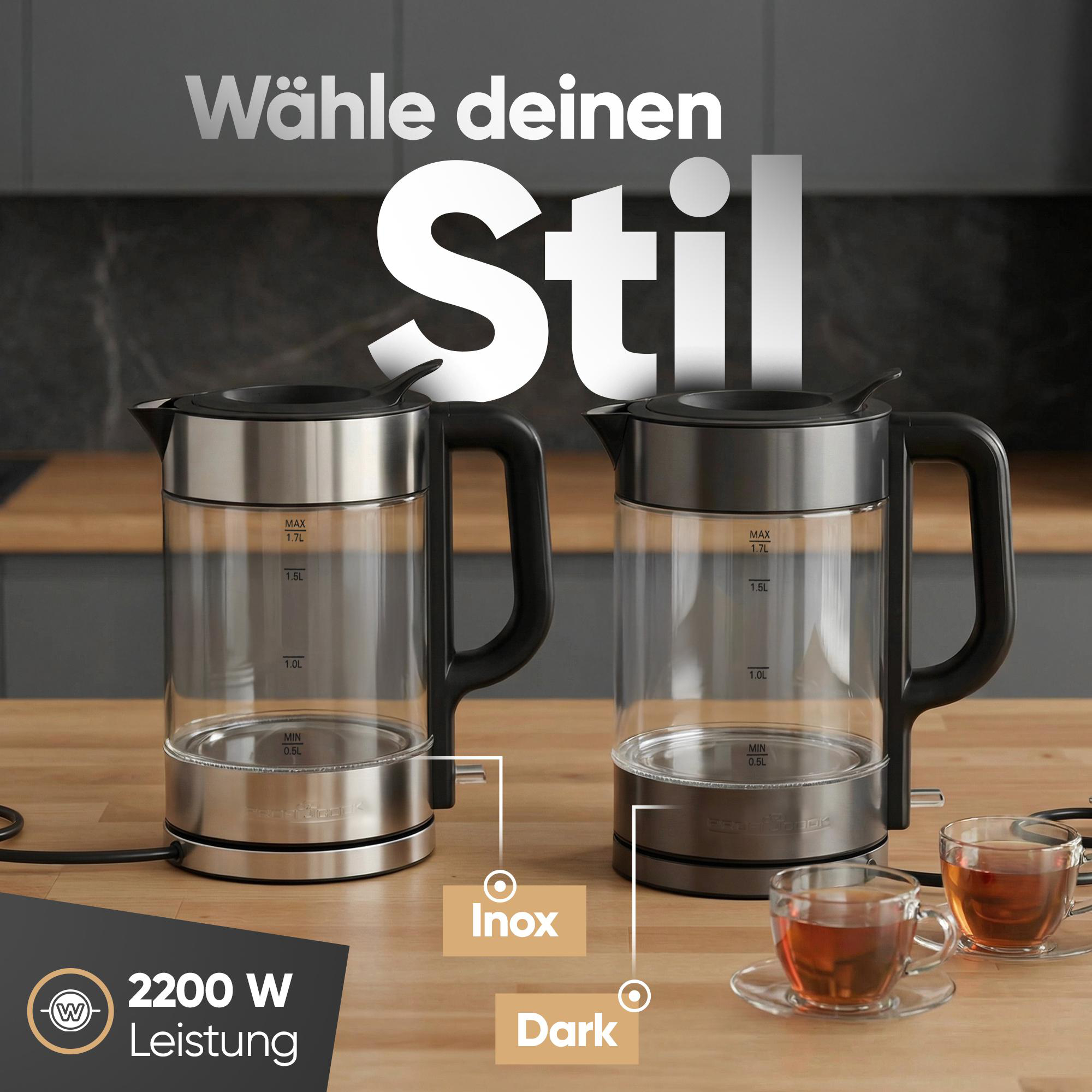 Zwei Glas-Wasserkocher, einer in Edelstahl, einer in Dunkel, mit Tassen Tee.