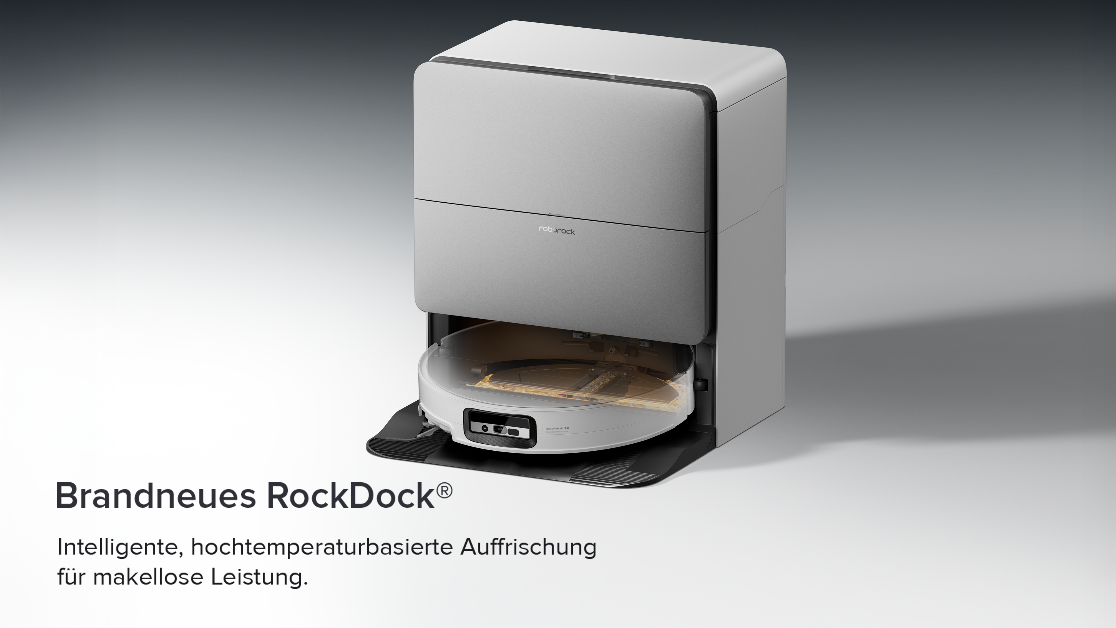 Ein grauer Roborock RockDock mit einem Saugroboter auf einer schwarzen Matte.