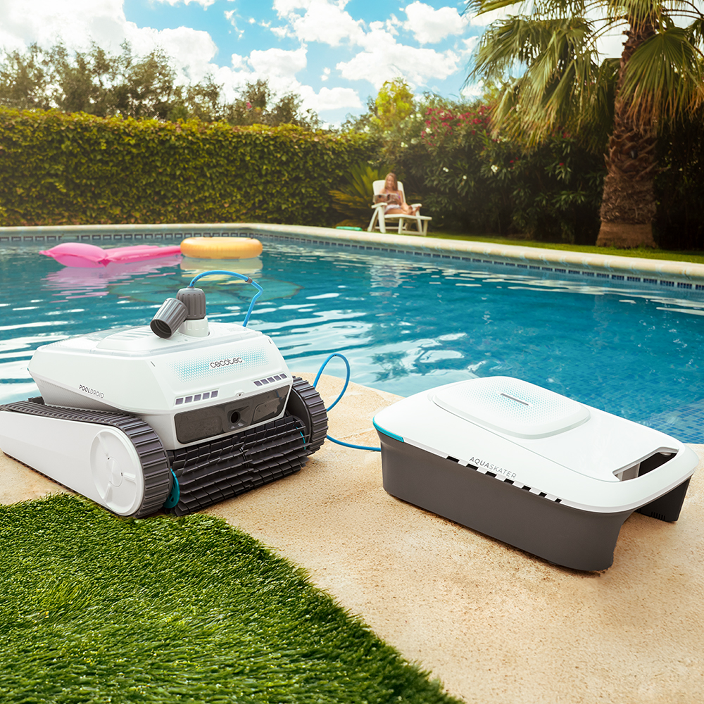 Robot de piscina y caja de control en el borde, mujer relajándose detrás.