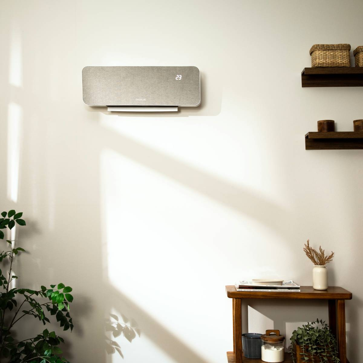 Un purificador de aire acondicionado plateado en una pared blanca con sombras.