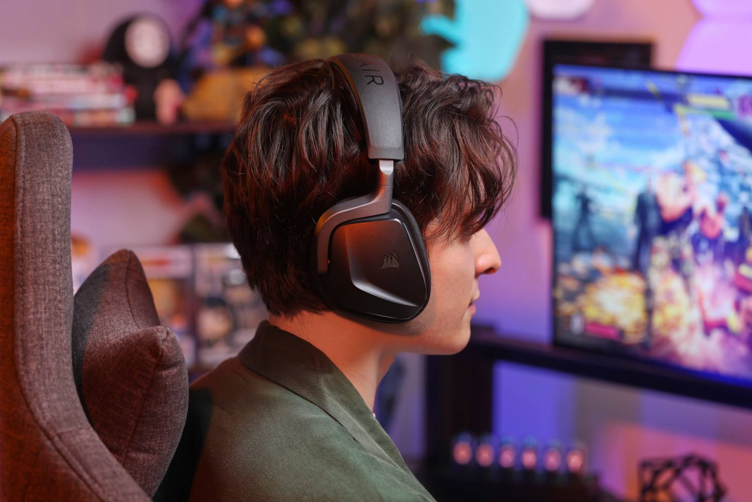 Un hombre con auriculares juega a un videojuego frente a una pantalla brillante.