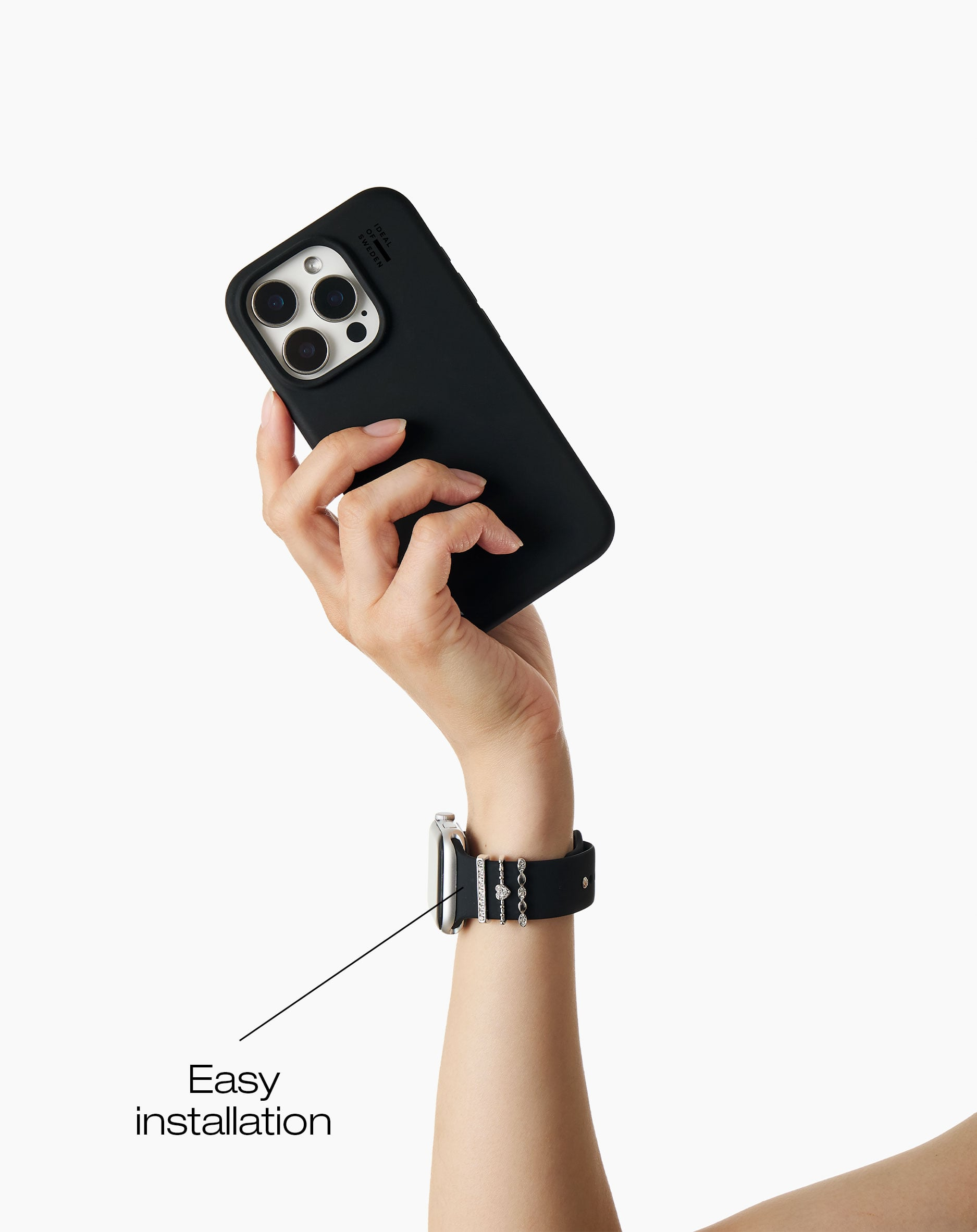 Hand hält ein schwarzes Handy mit drei Kameras. Ein Arm trägt eine Uhr.