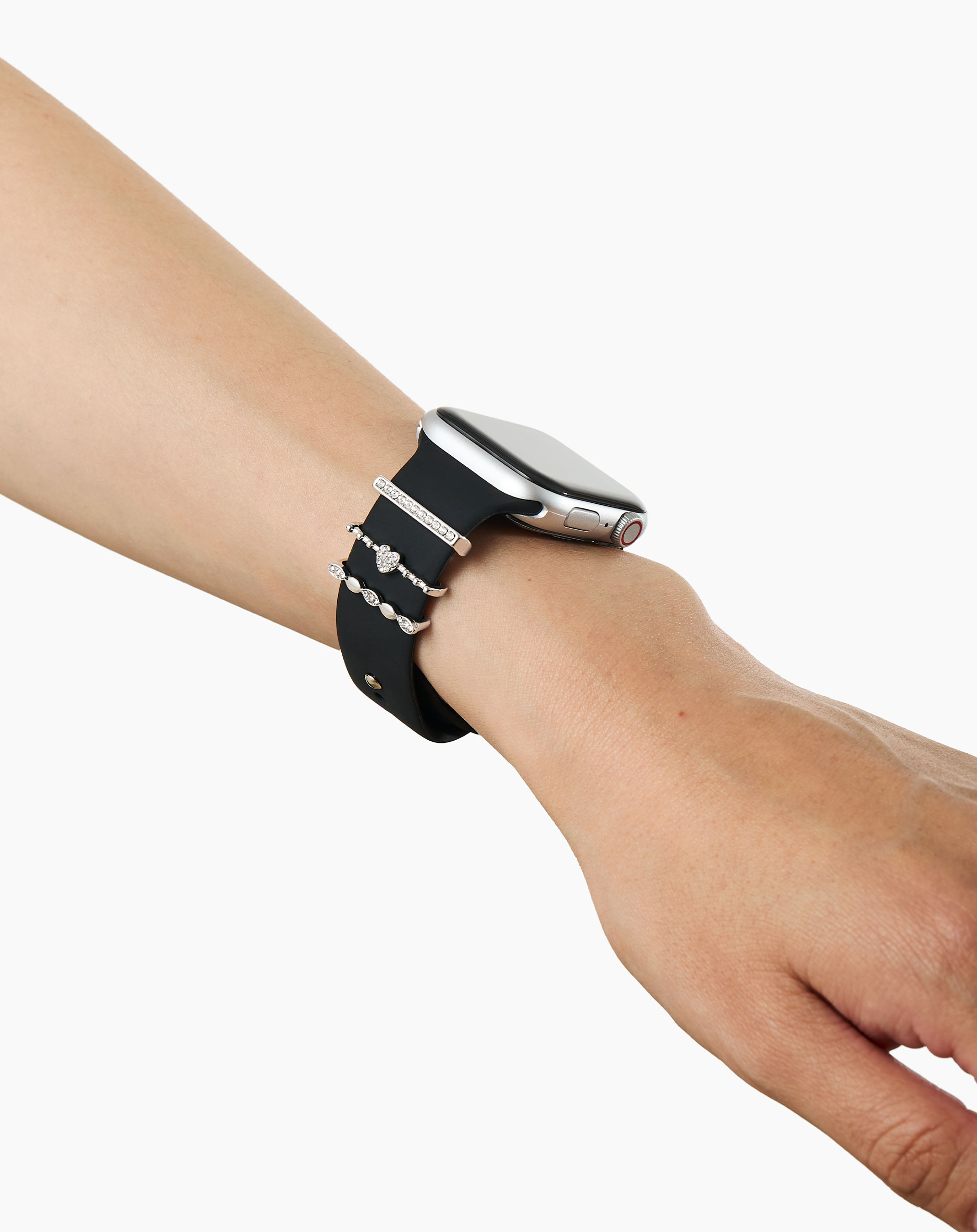 Eine Hand mit einer schwarzen Smartwatch und drei glitzernden Charm-Armbändern.