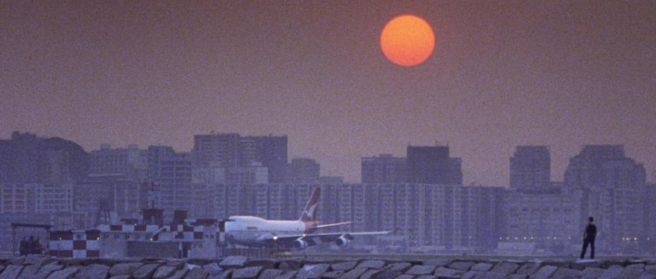 Ein Flugzeug rollt auf einem Rollfeld vor einer Stadtkulisse bei Sonnenuntergang.