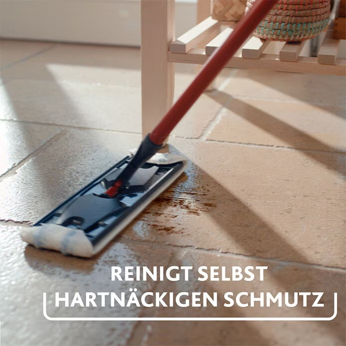 Ein Mopp mit rotem Stiel reinigt einen Steinboden.