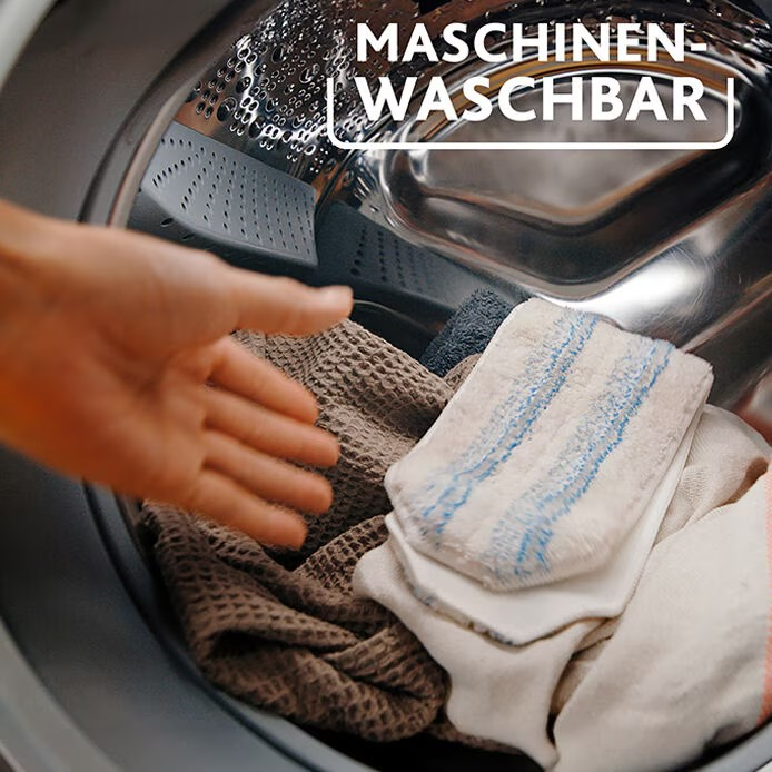 Hand legt Kleidung in eine Waschmaschine, Text: Maschinen-Waschbar