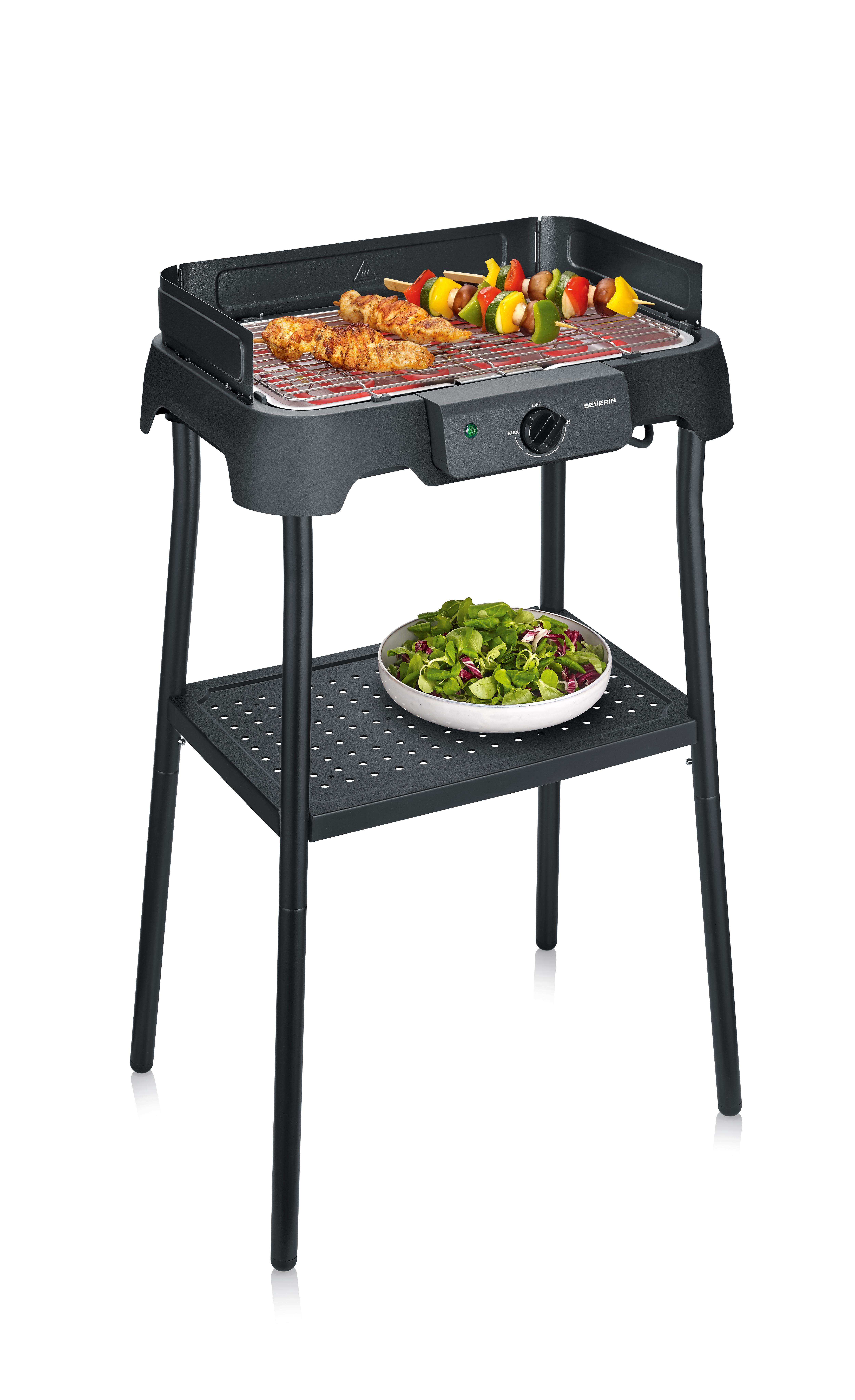 Ein elektrischer Grill mit Hähnchen und Gemüsespießen, daneben ein Salat.