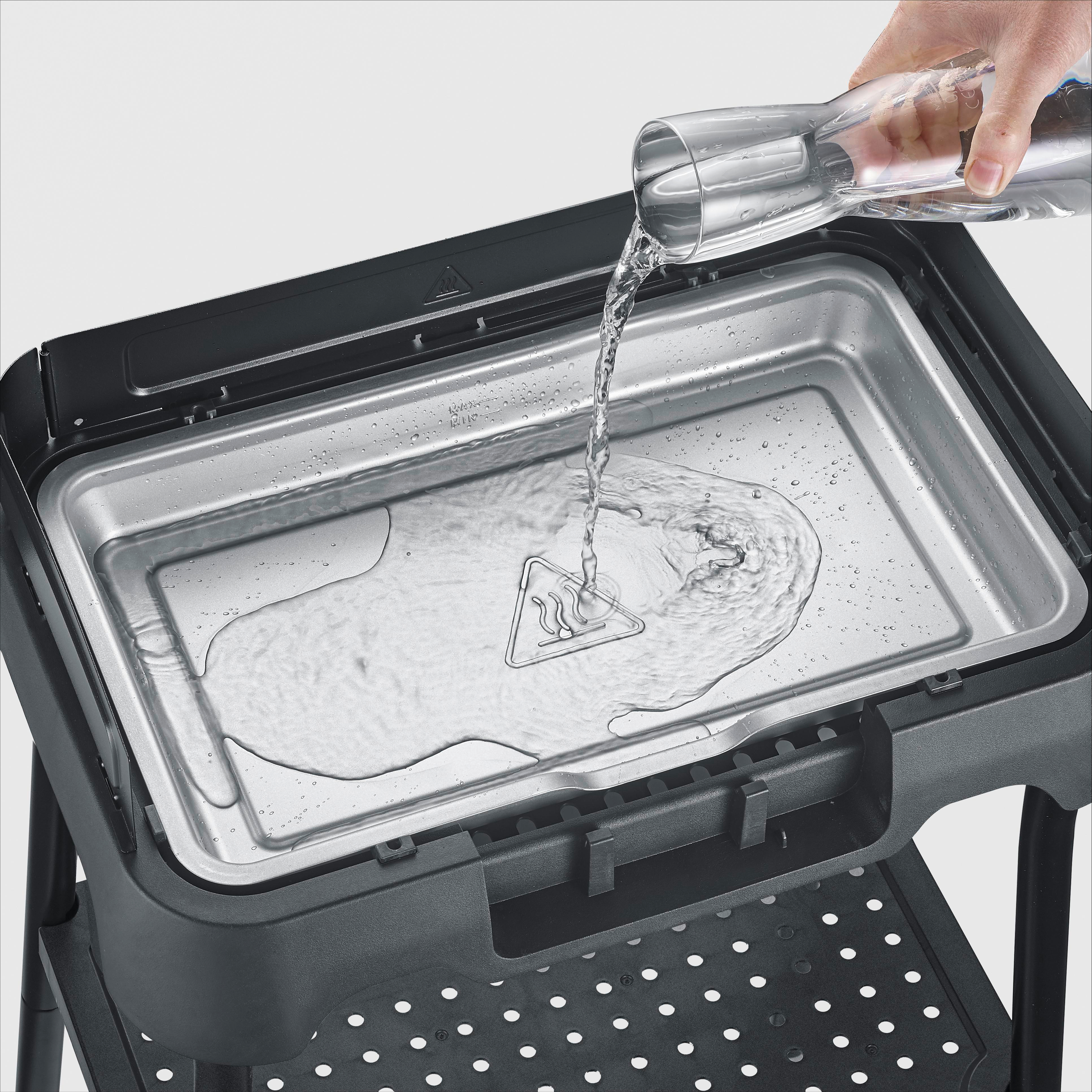 Wasser wird aus einer Glasflasche in eine Grillpfanne gegossen.