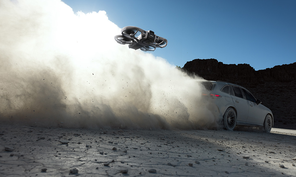 Dron leci nad samochodem jadącym po piaszczystej nawierzchni.