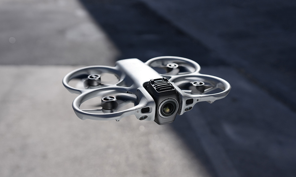 Dron z kamerą unosi się nad szarą powierzchnią.