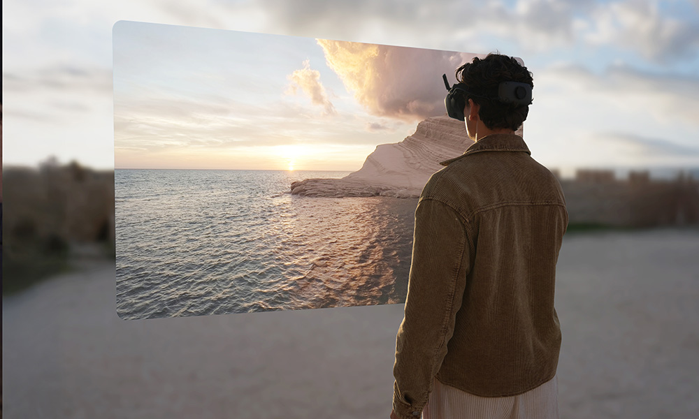 Osoba w goglach VR ogląda cyfrowy zachód słońca nad białymi klifami.