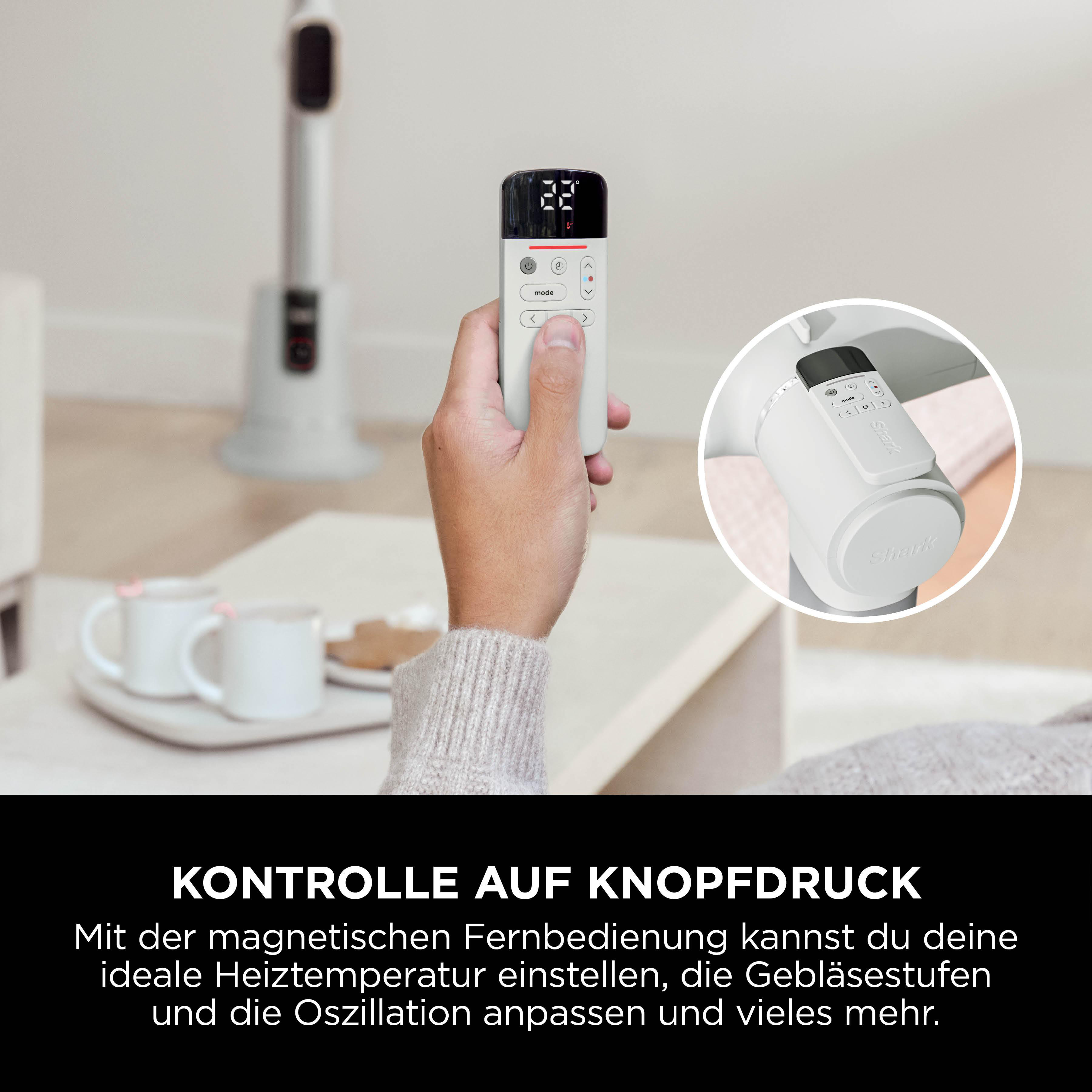 Eine Hand hält eine weiße Fernbedienung mit Digitalanzeige. Ein Heizlüfter ist im Hintergrund.