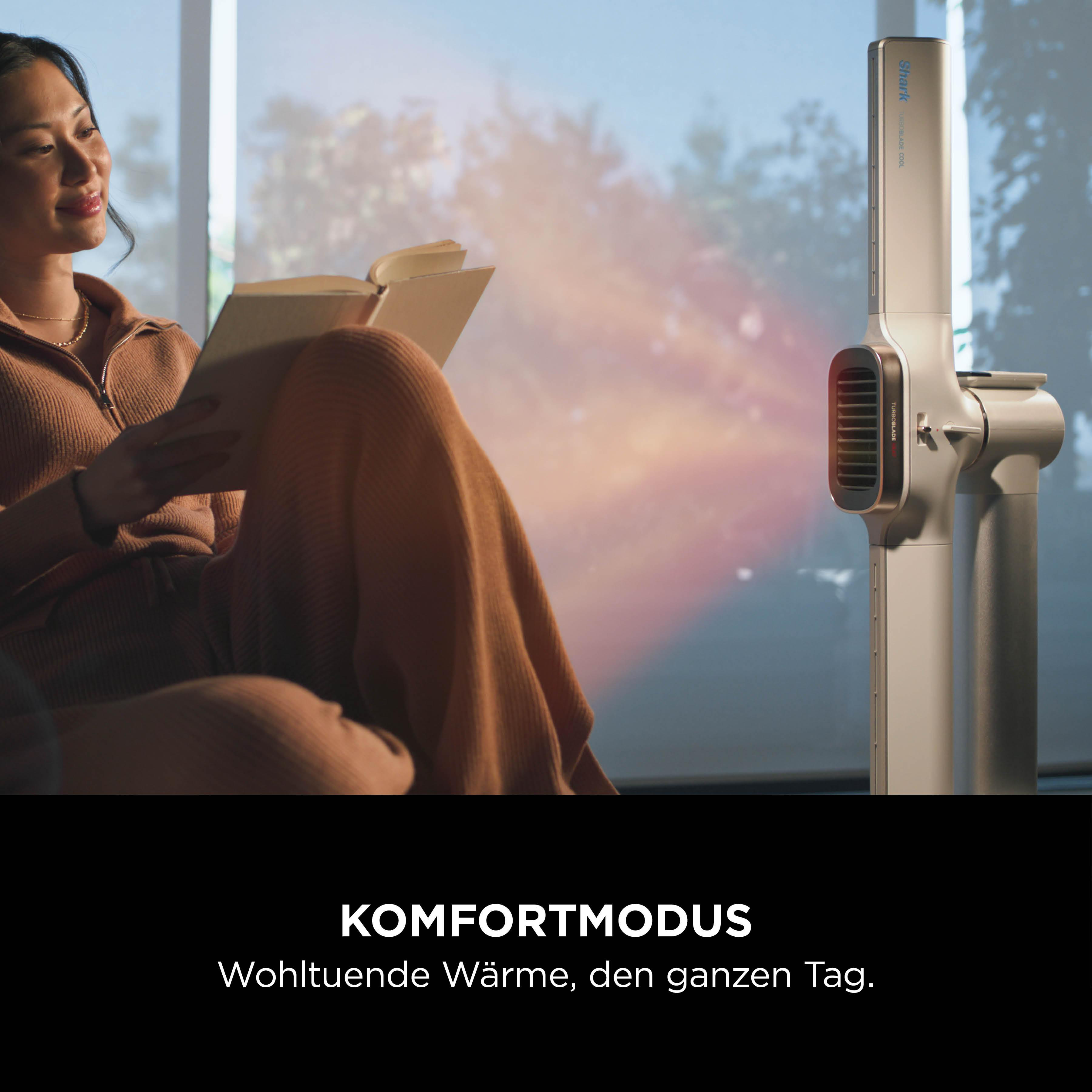 Eine Frau liest ein Buch neben einem Heizlüfter. Komfortmodus.