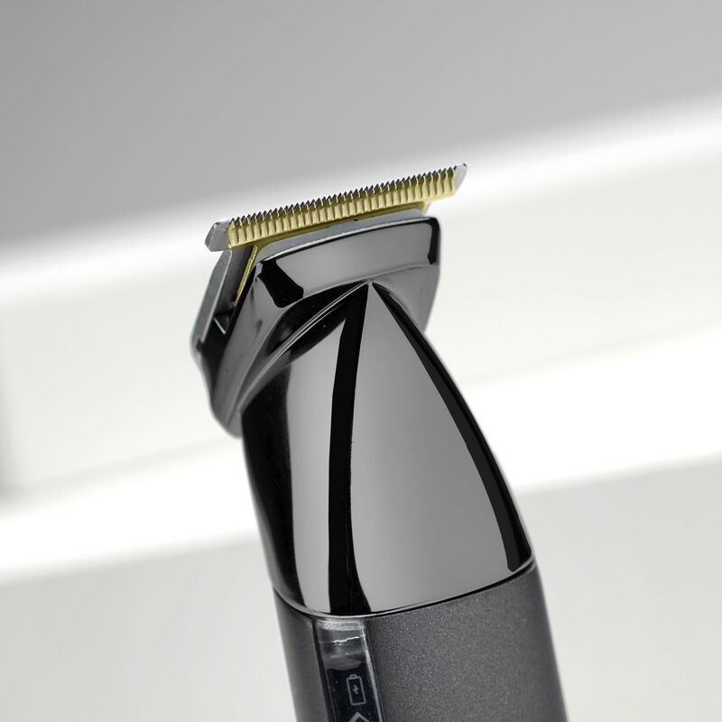 Detailaufnahme eines schwarzen Trimmers mit goldenen Klingen und einem Batteriesymbol.