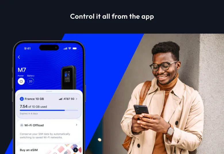 Homme avec lunettes et manteau beige regarde son téléphone. Le téléphone montre une app avec données.