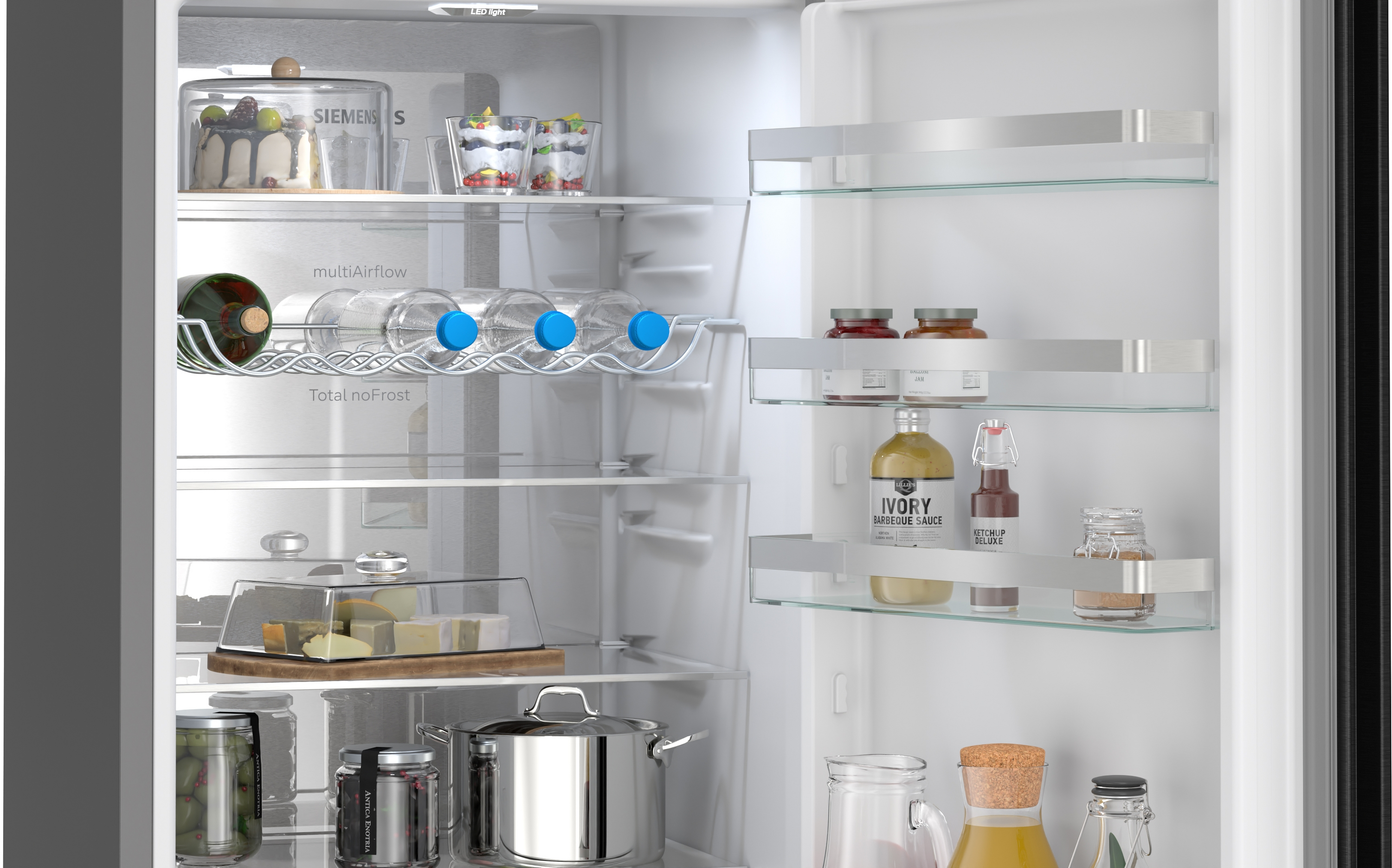 Gefüllter Kühlschrank mit Kuchen, Obst, Flaschen, Gläsern, Käse und Gewürzen.