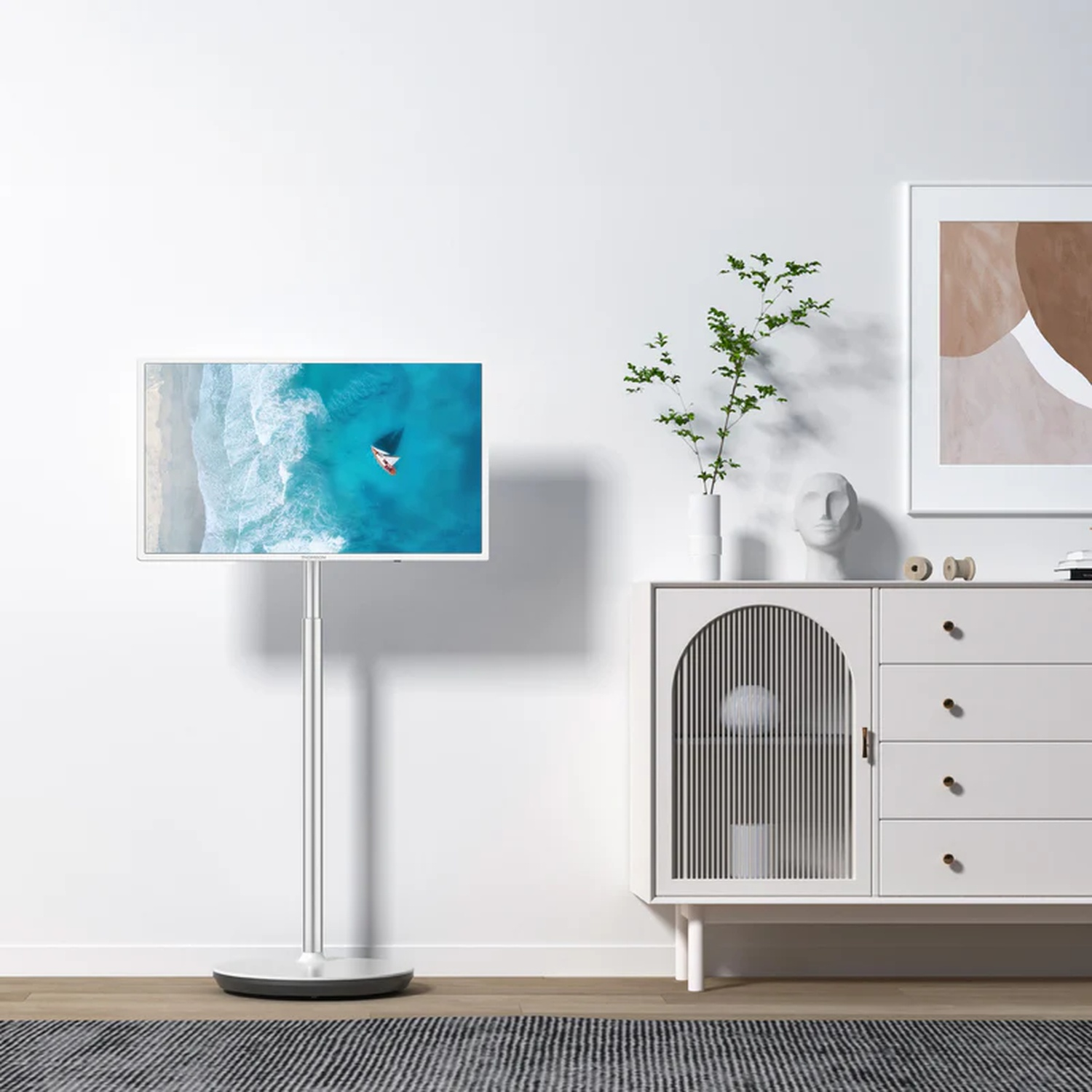 Un TV su supporto mostra una barca sul mare. Accanto, una credenza con arte.