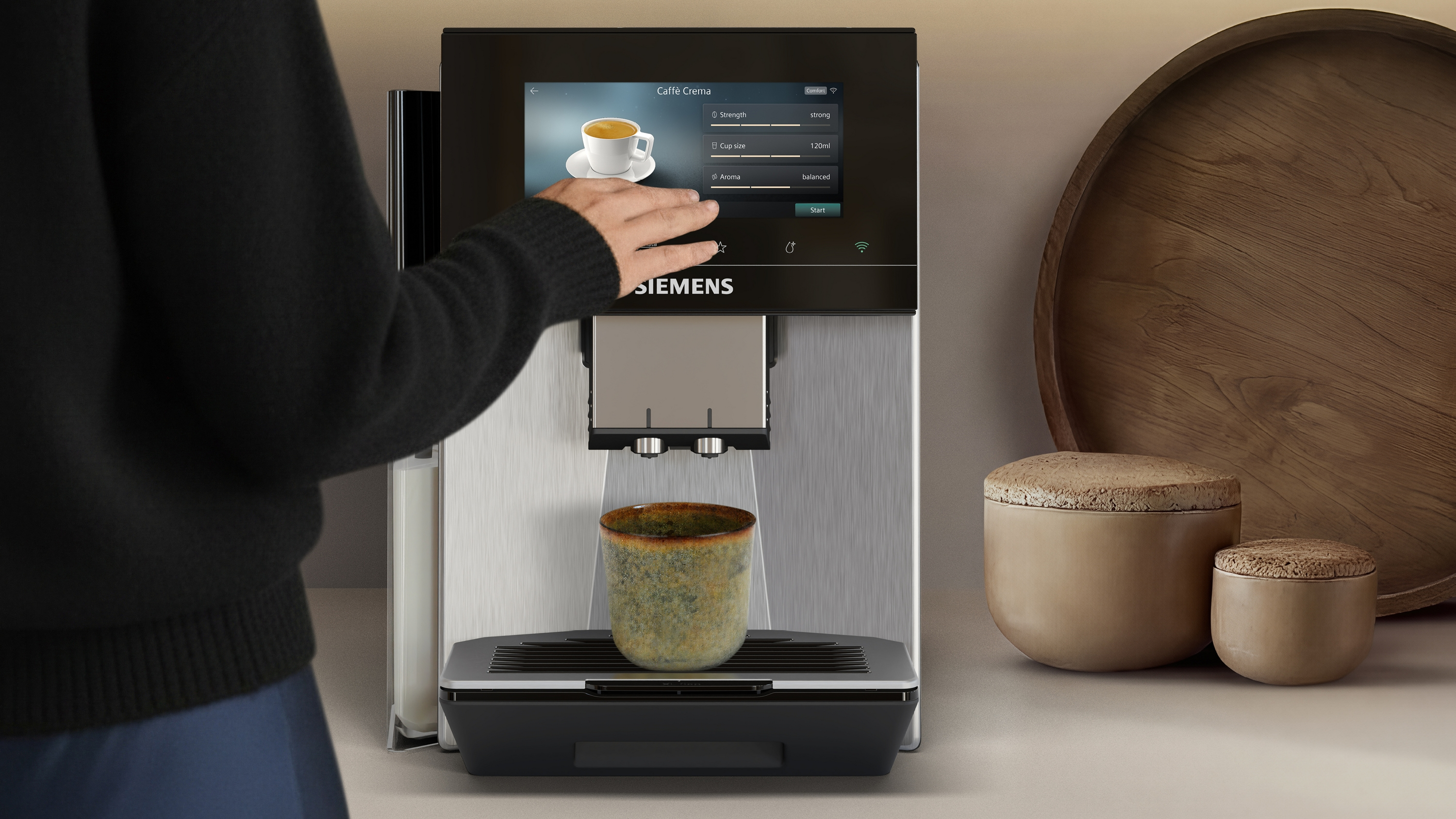 Eine Hand bedient ein Siemens Kaffeevollautomat mit Touchscreen.