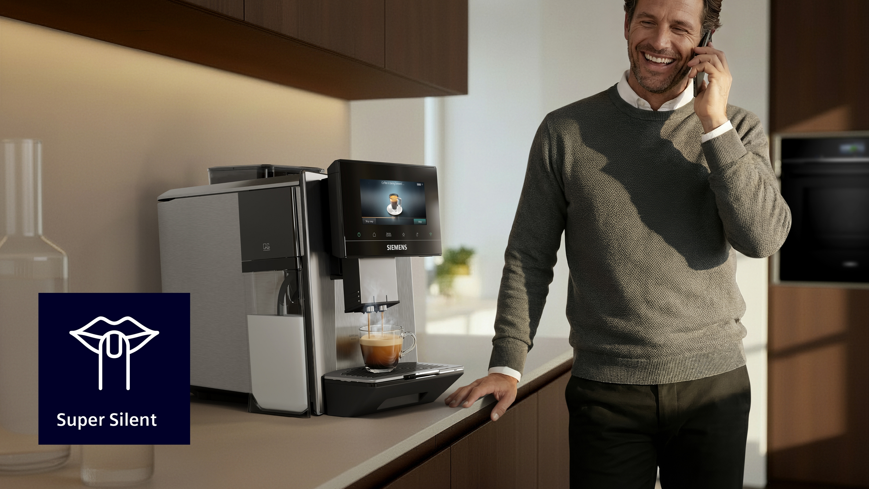 Kaffeemaschine brüht Kaffee, Mann telefoniert glücklich daneben.
