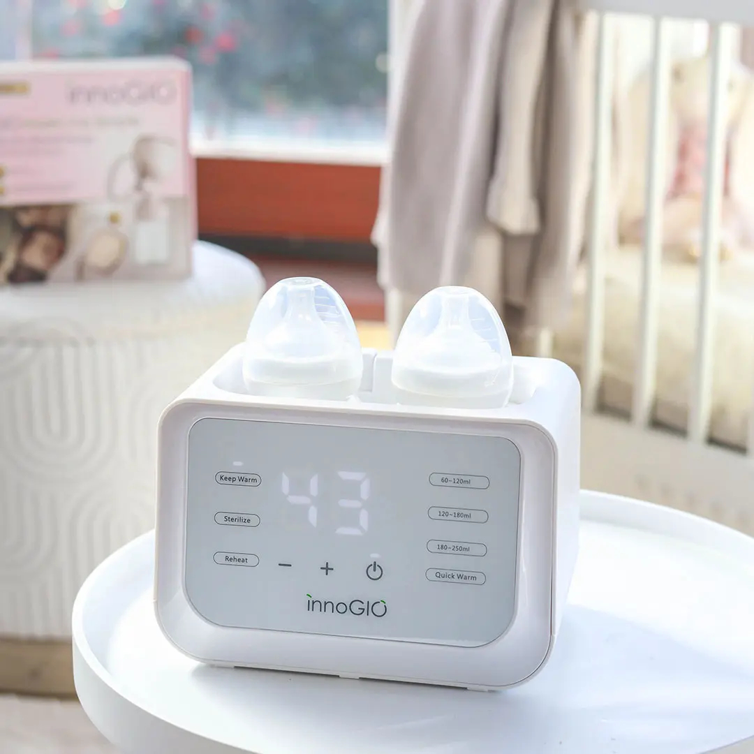 Biały podgrzewacz do butelek z dwoma butelkami stoi na stole. Wyświetlacz cyfrowy pokazuje 43.