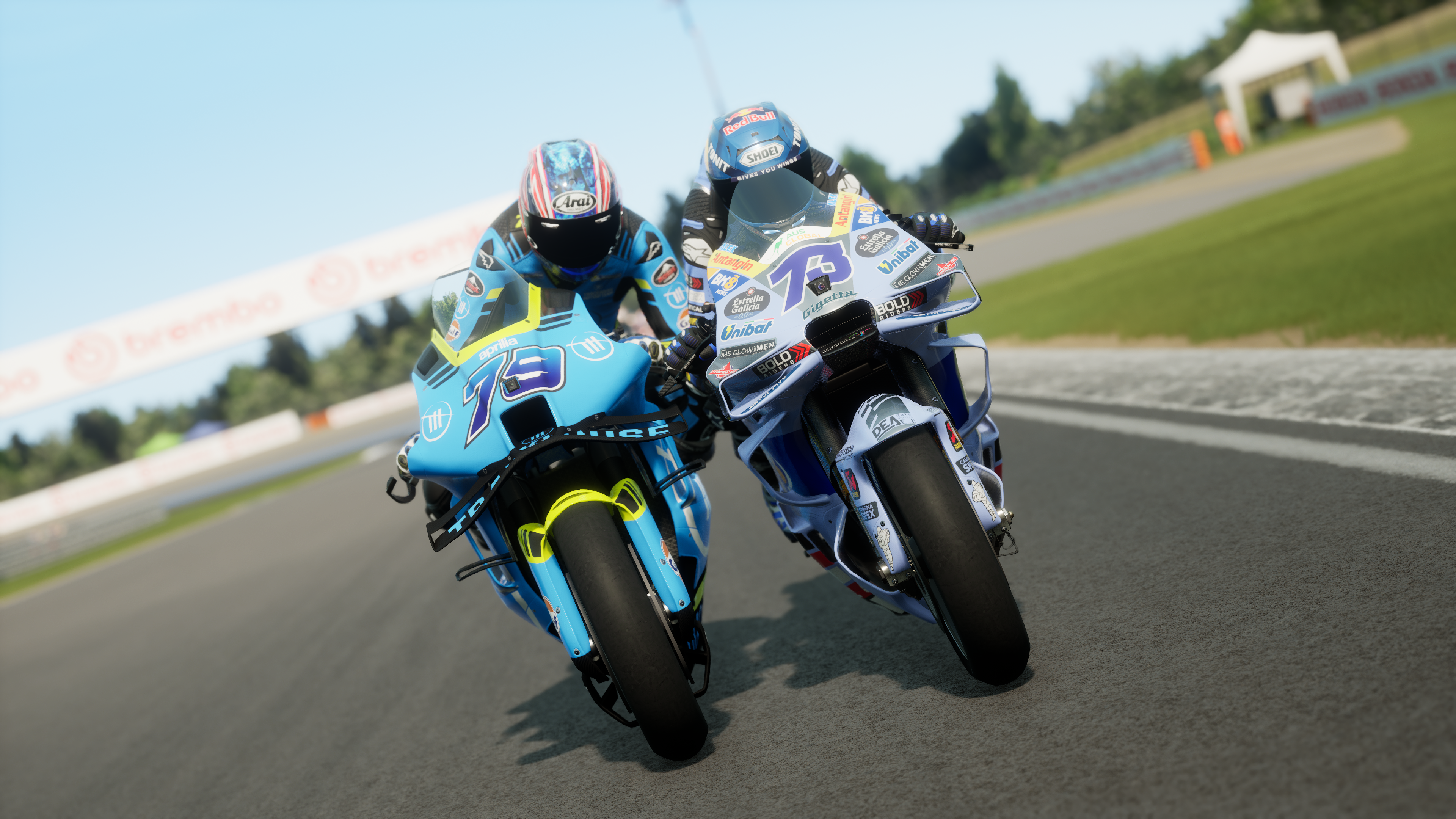 Deux motos de course sur une piste, pilotes en combinaisons bleues, journée ensoleillée.