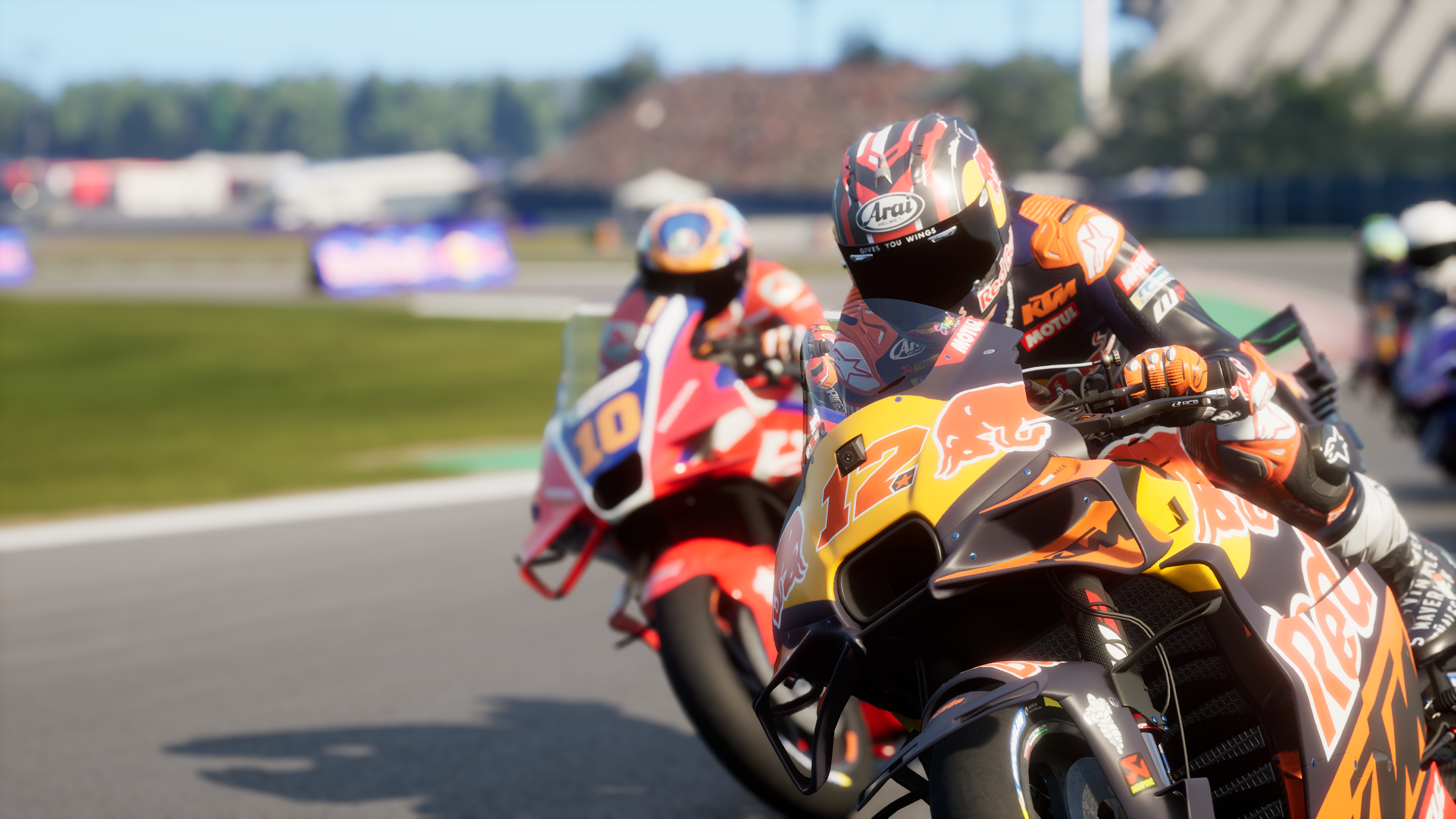 Coureurs en tenue orange sur des motos sur un circuit.