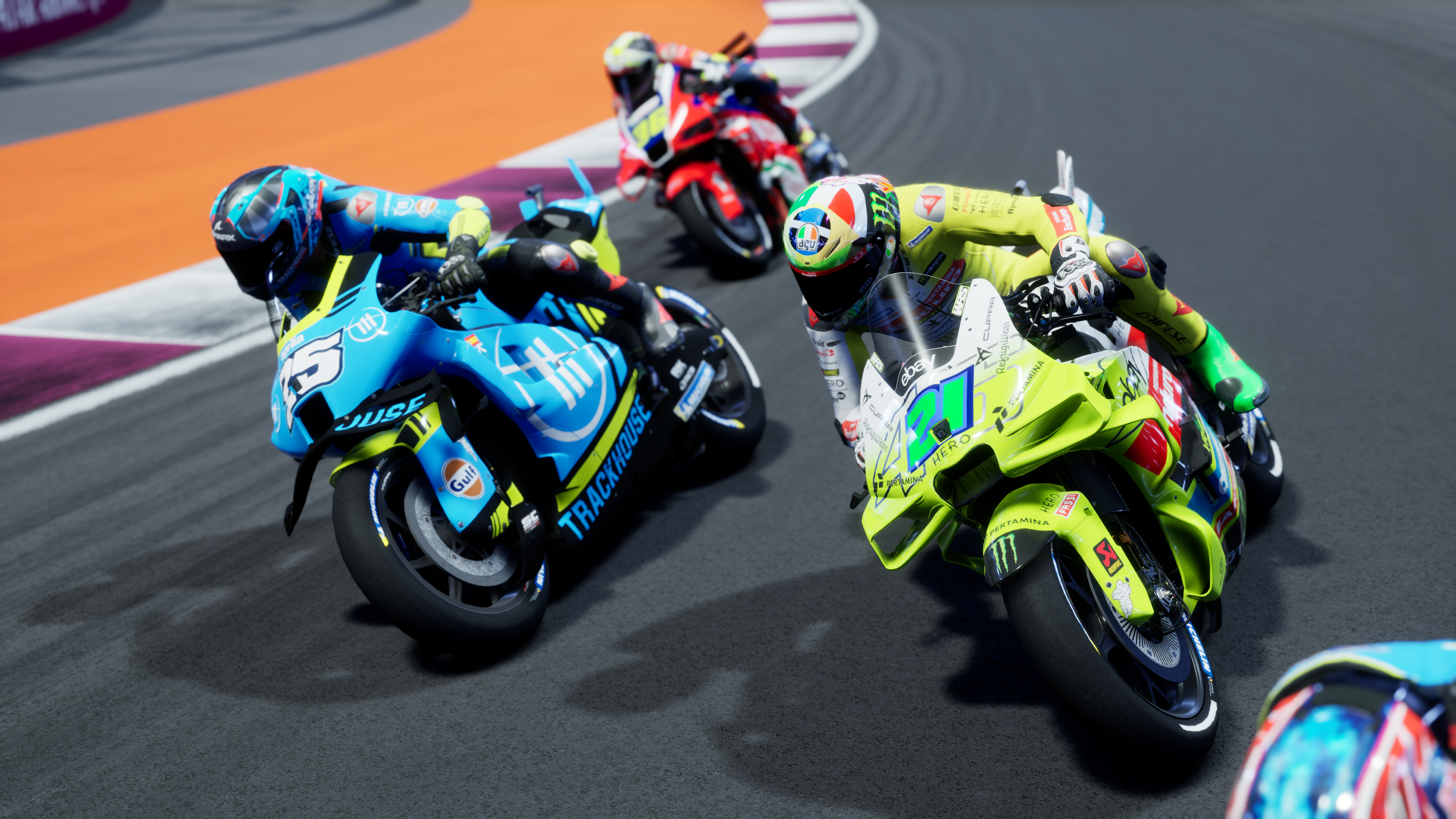 Des motocyclistes font la course sur une piste avec des motos bleues, jaunes et rouges.