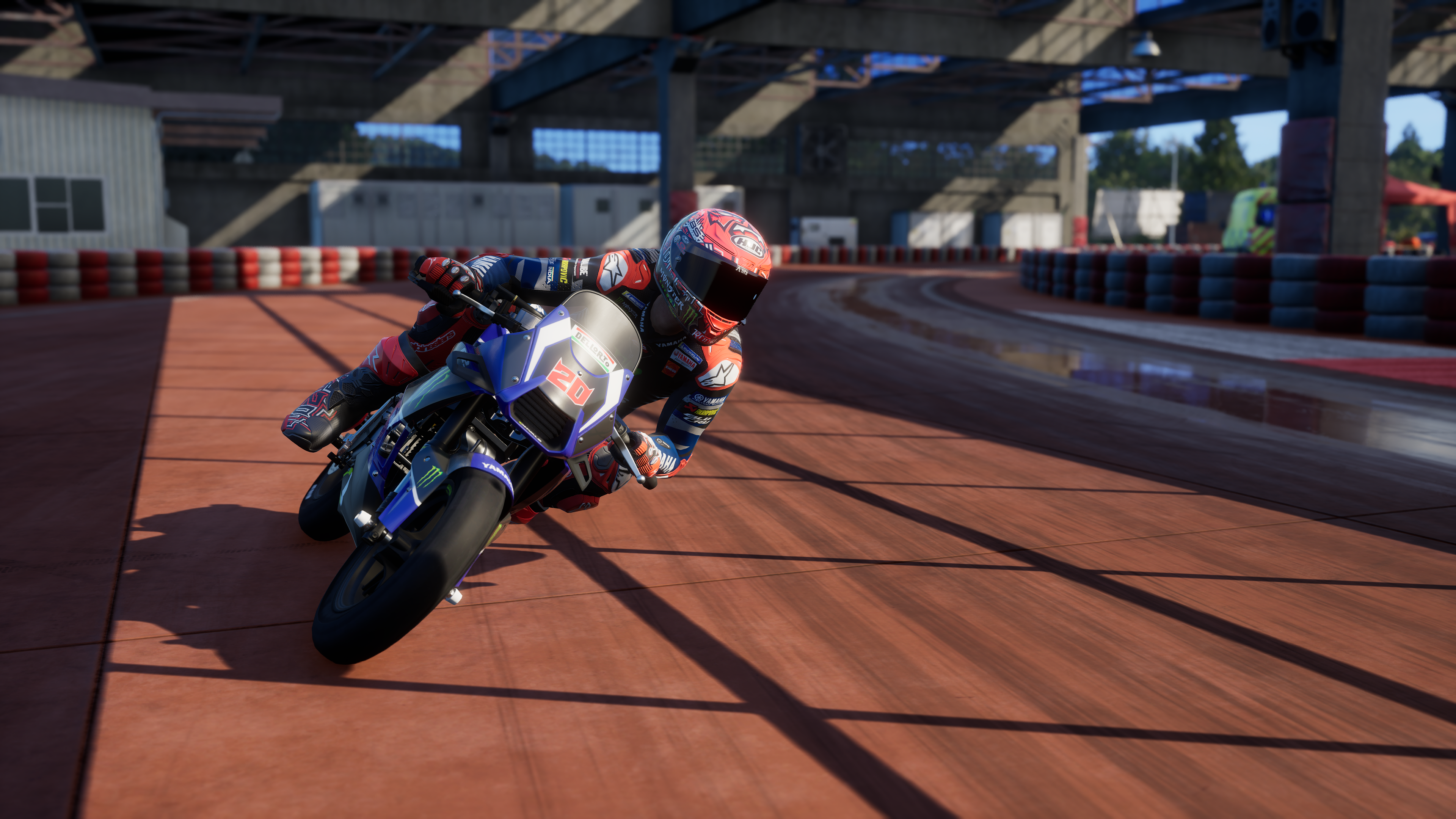 Un motocycliste en tenue bleue et rouge se penche dans un virage sur un circuit.