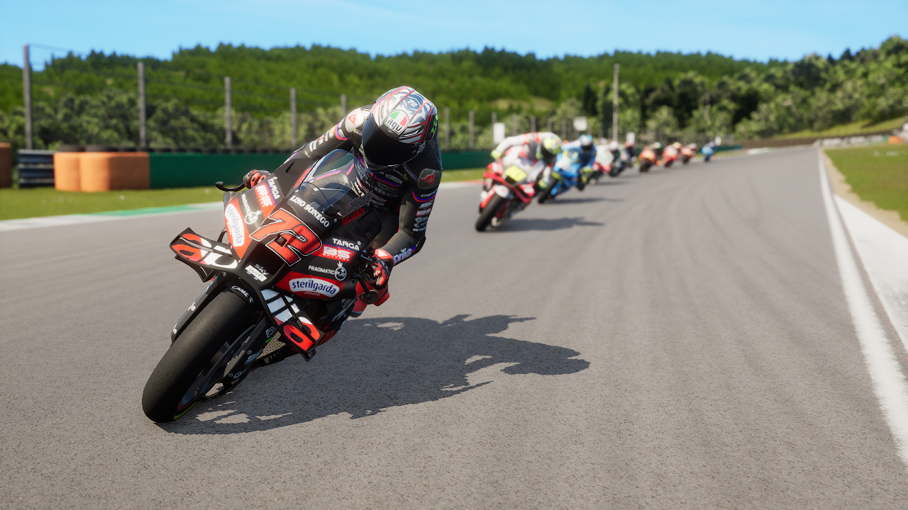 Des motards en pleine course sur un circuit, d'autres motos en arrière-plan.