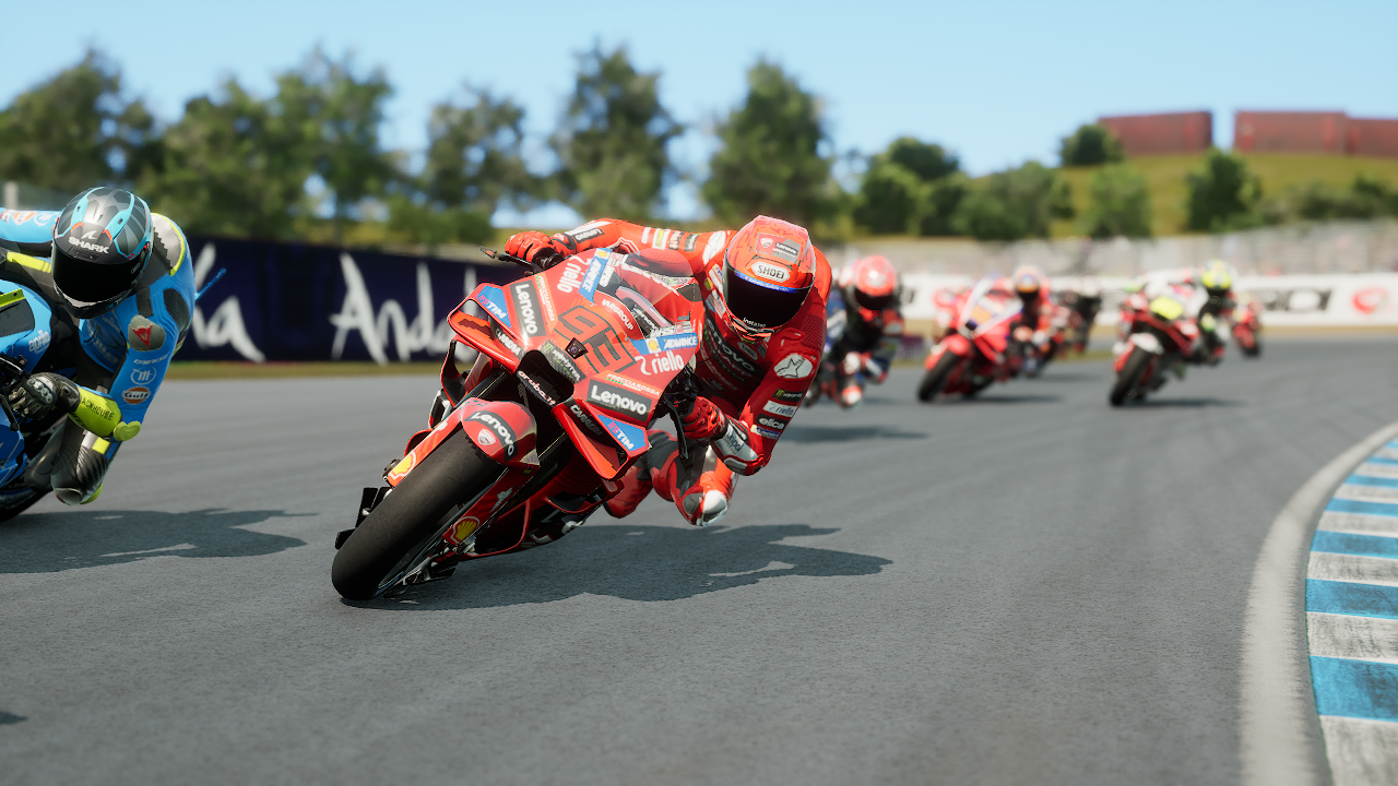 Des motocyclistes en rouge et bleu prennent un virage sur un circuit.