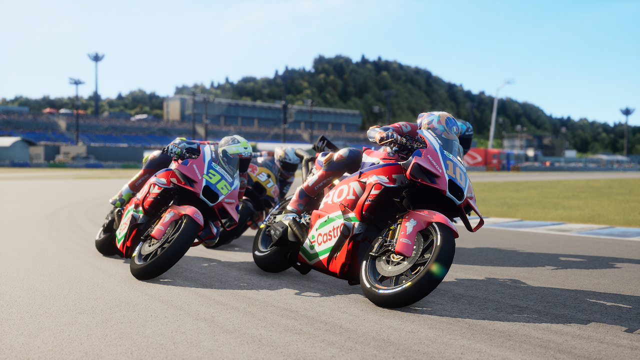 Des motocyclistes en combinaison rouge prennent un virage sur une piste avec des spectateurs.