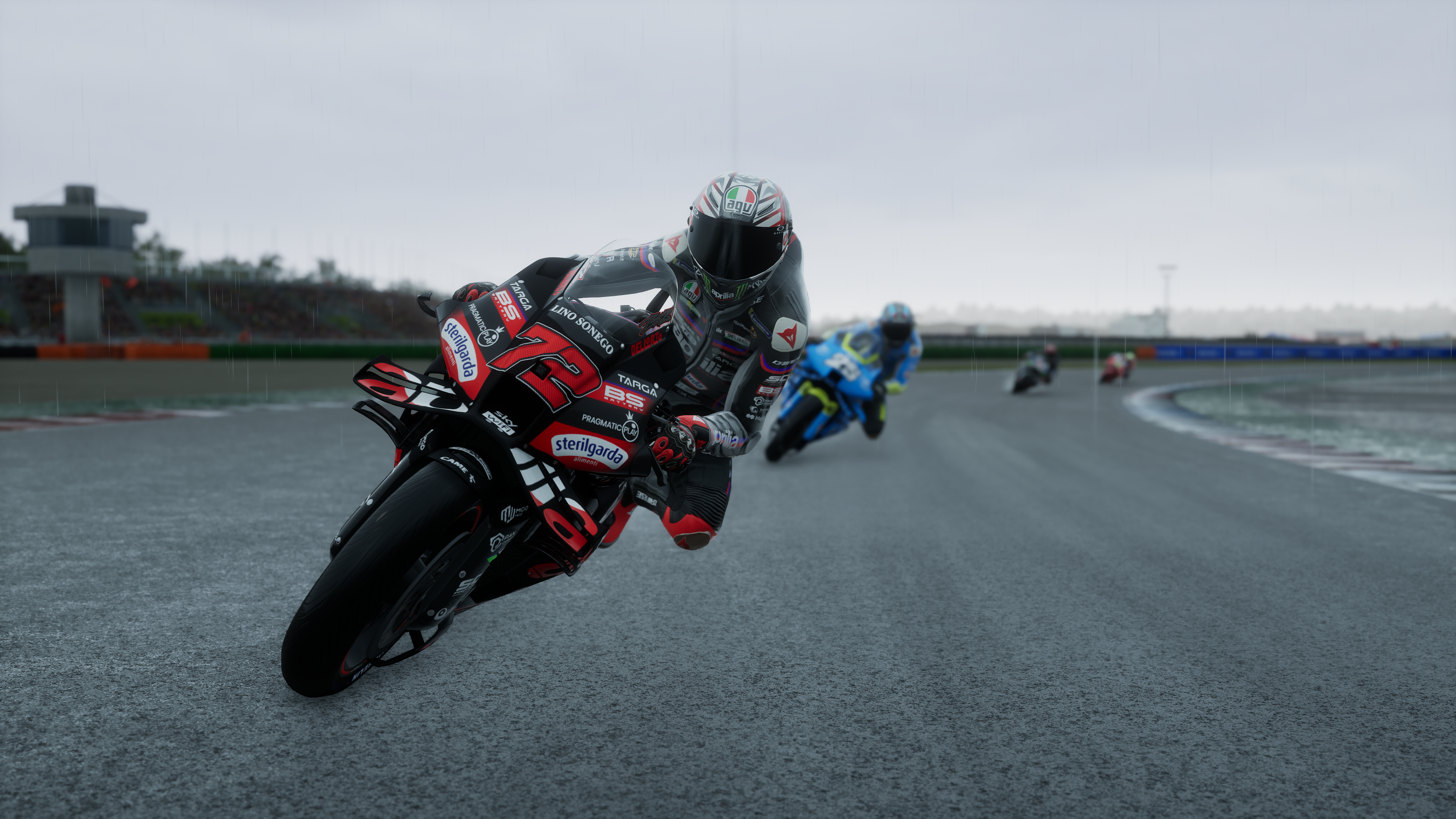 Des motocyclistes font la course sous la pluie sur une piste mouillée.