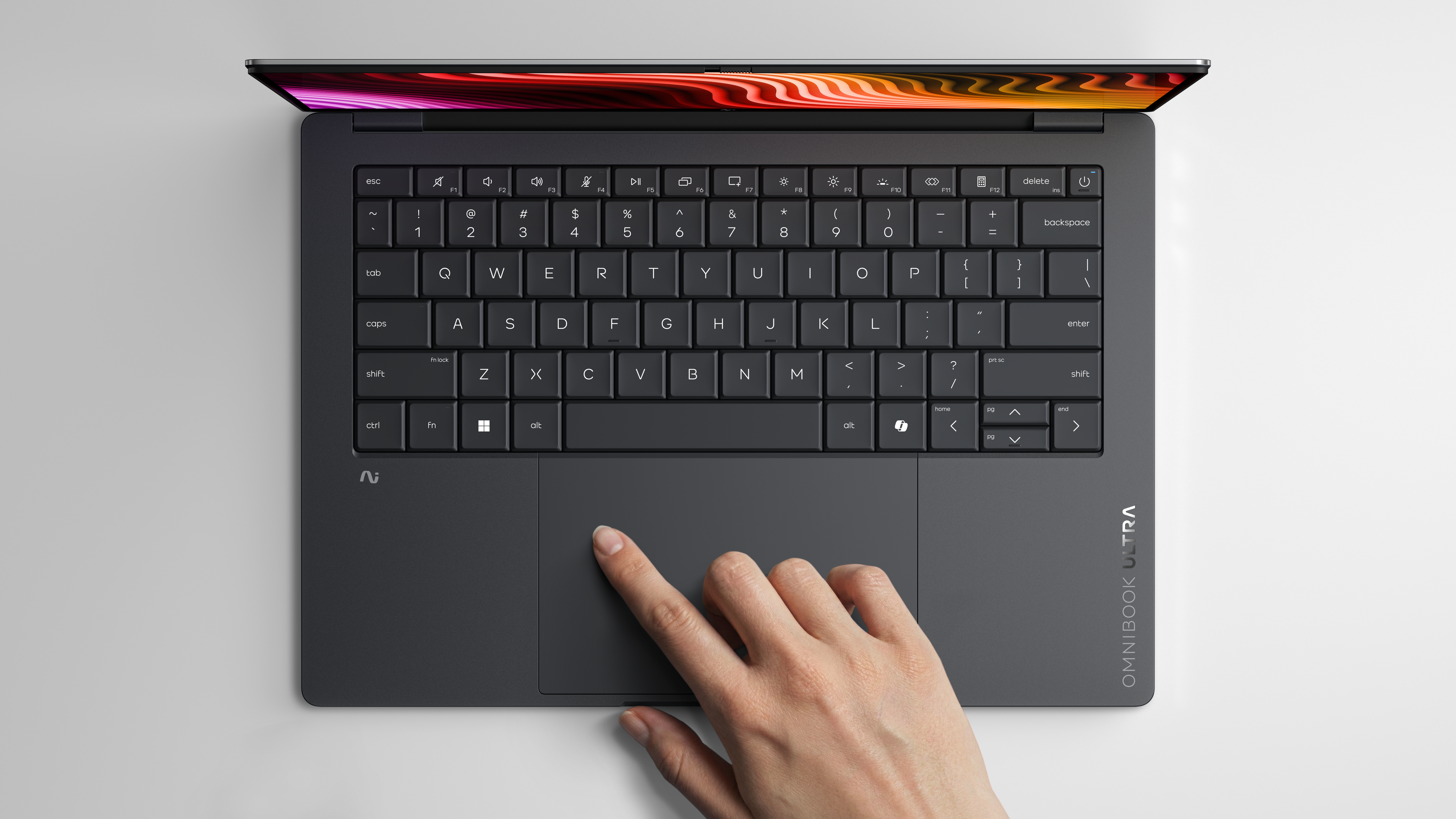 Dłoń dotyka gładzika ciemnego laptopa z podświetlonym ekranem.