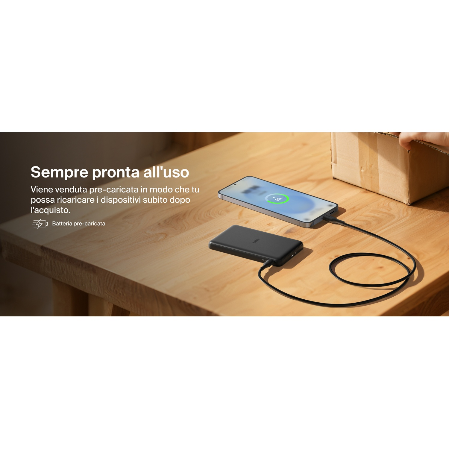 Un power bank nero carica uno smartphone su un tavolo di legno.