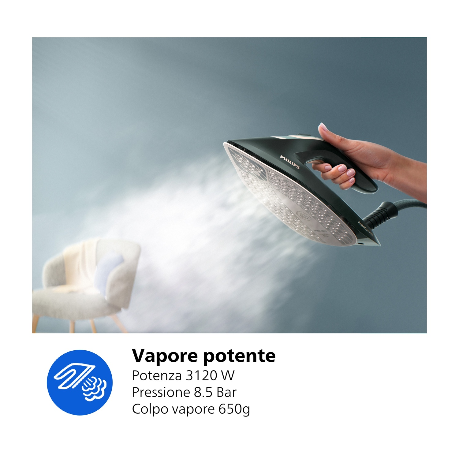 Una mano tiene un ferro scuro, rilasciando vapore. Una sedia sullo sfondo.