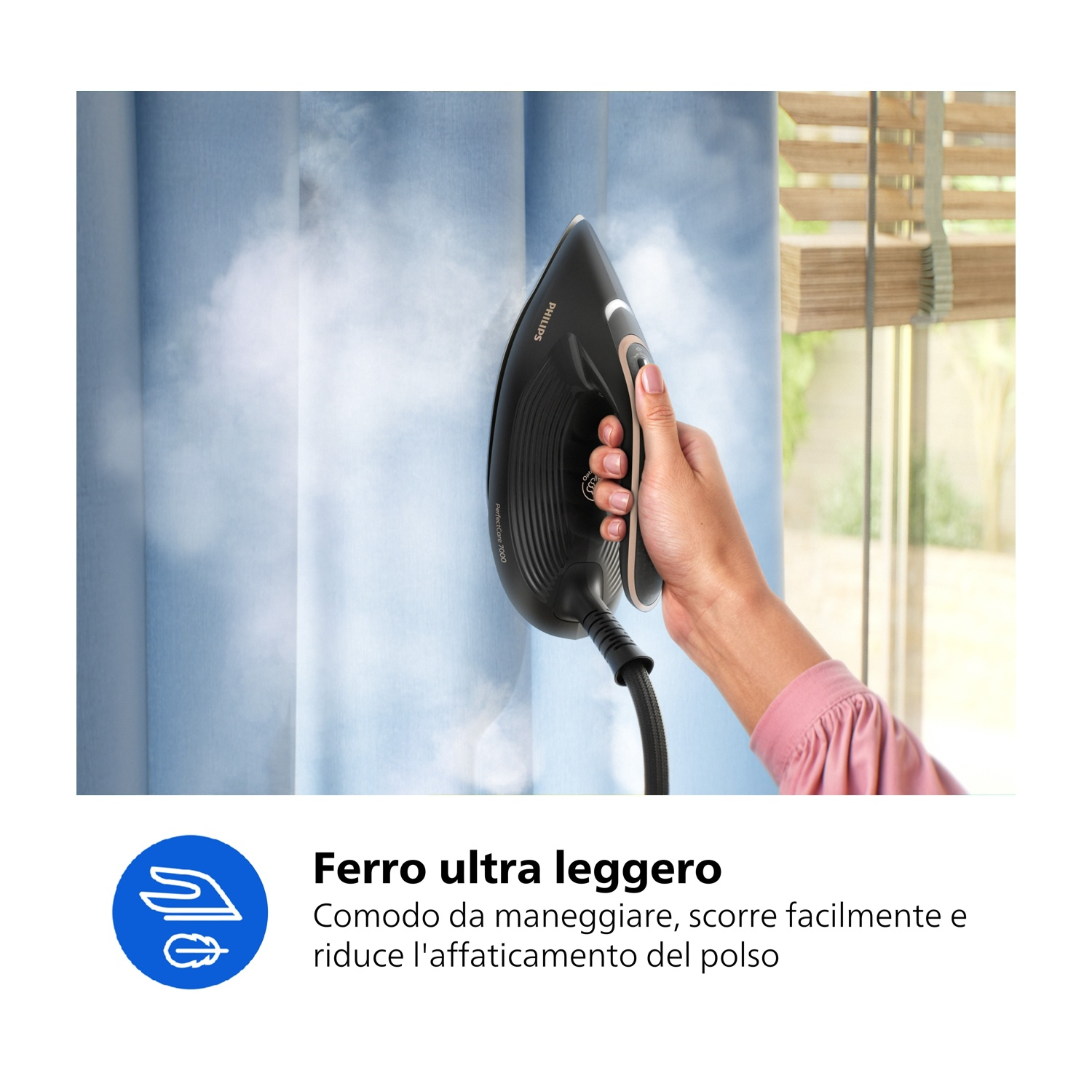 Una mano stira una tenda blu con vapore. Si tiene un ferro Philips.