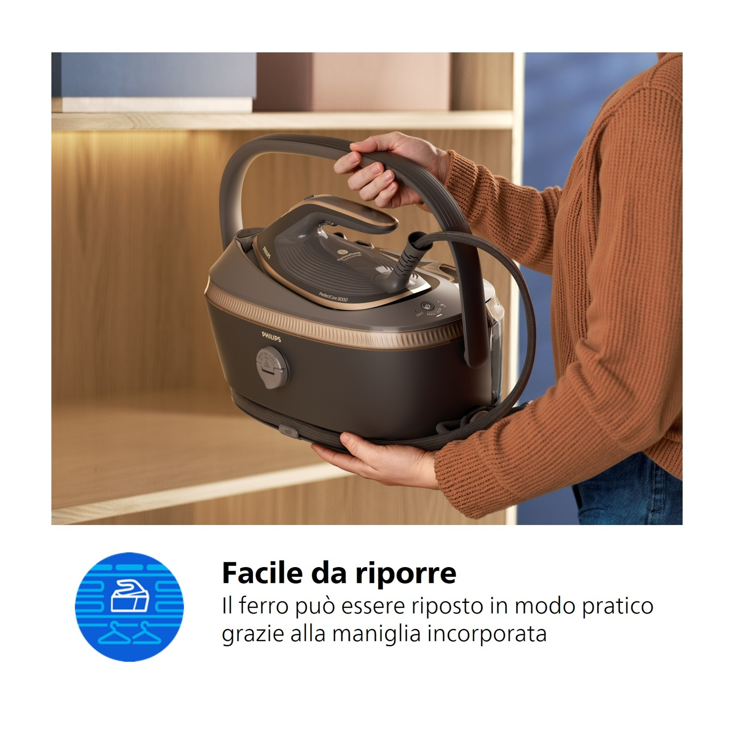 Una persona tiene un ferro da stiro a vapore scuro con accenti argento e manico.