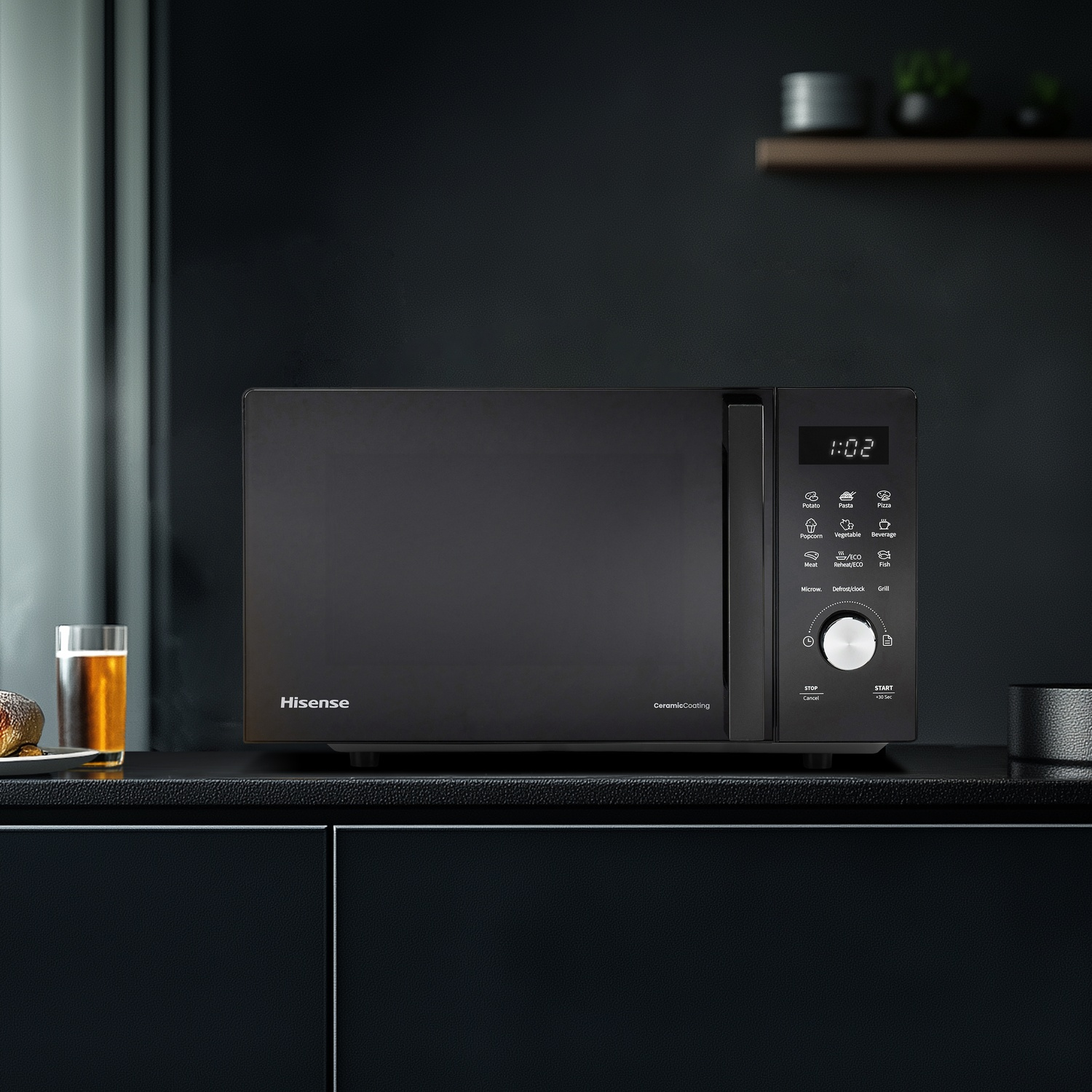 Un forno a microonde Hisense nero con display digitale su un piano di lavoro accanto a un bicchiere di birra.
