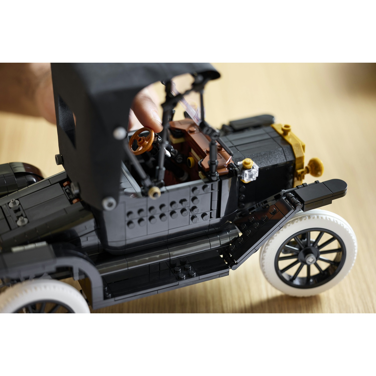 Una persona che assembla un'auto Lego nera con pneumatici bianchi e volante.
