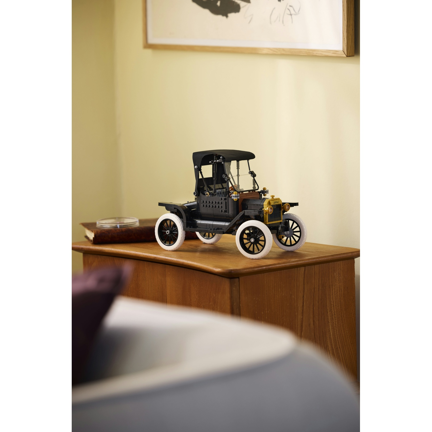 Una macchinina nera con pneumatici bianchi siede su una cassettiera di legno.
