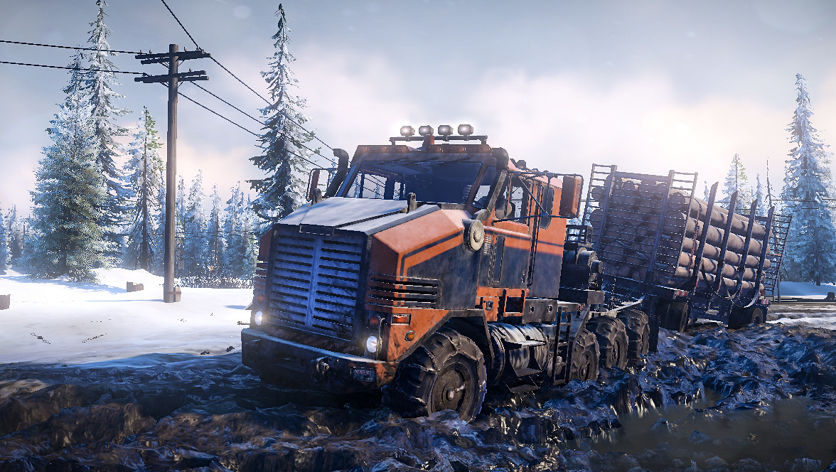 Ein orange-blauer LKW mit Holz beladen fährt durch schlammiges, verschneites Gelände.