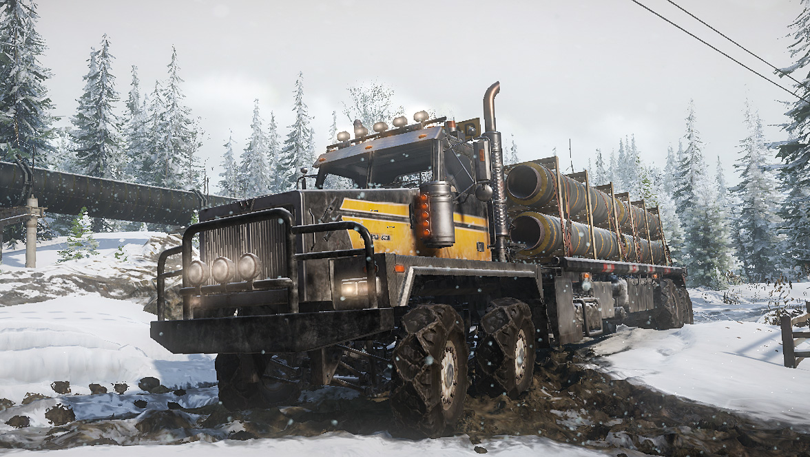 Ein gelber und schwarzer LKW mit Rohren beladen fährt durch Schnee.