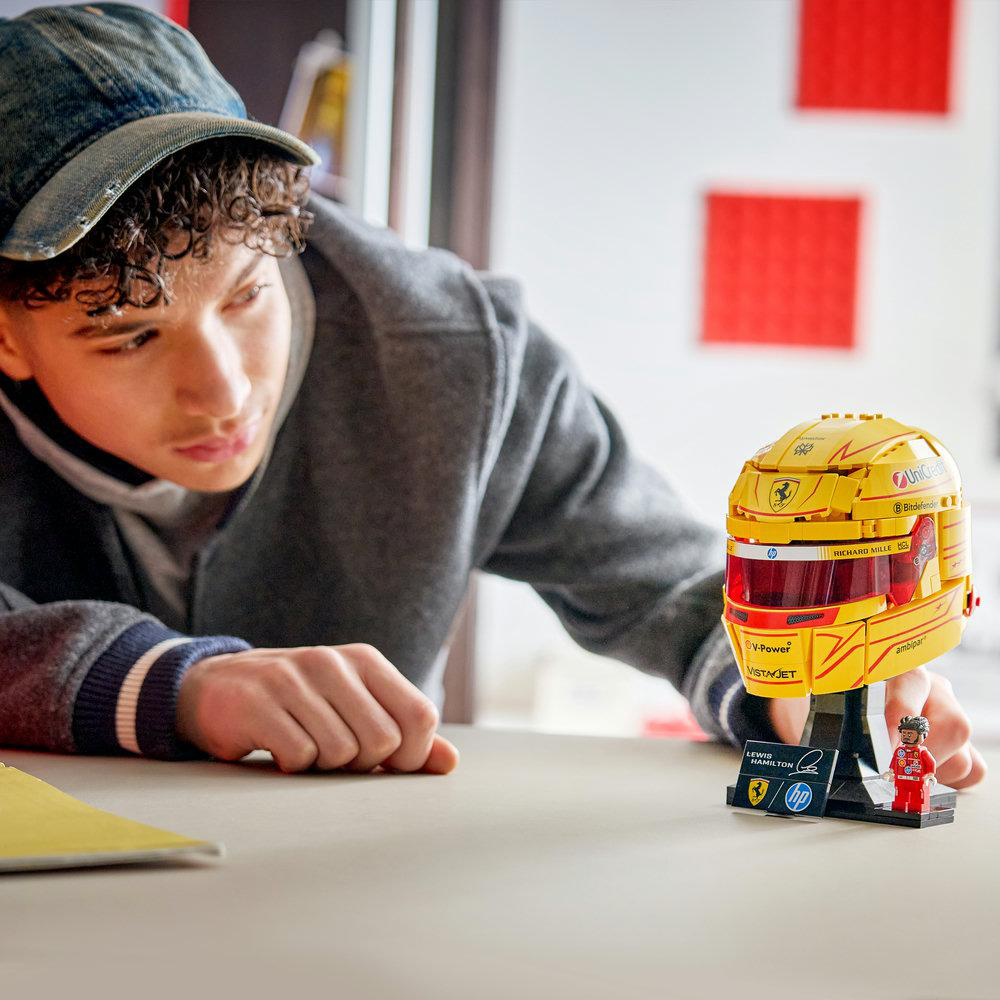 Junge mit Jeanscap und grauer Jacke schaut auf gelben Lego Formel-1-Helm.